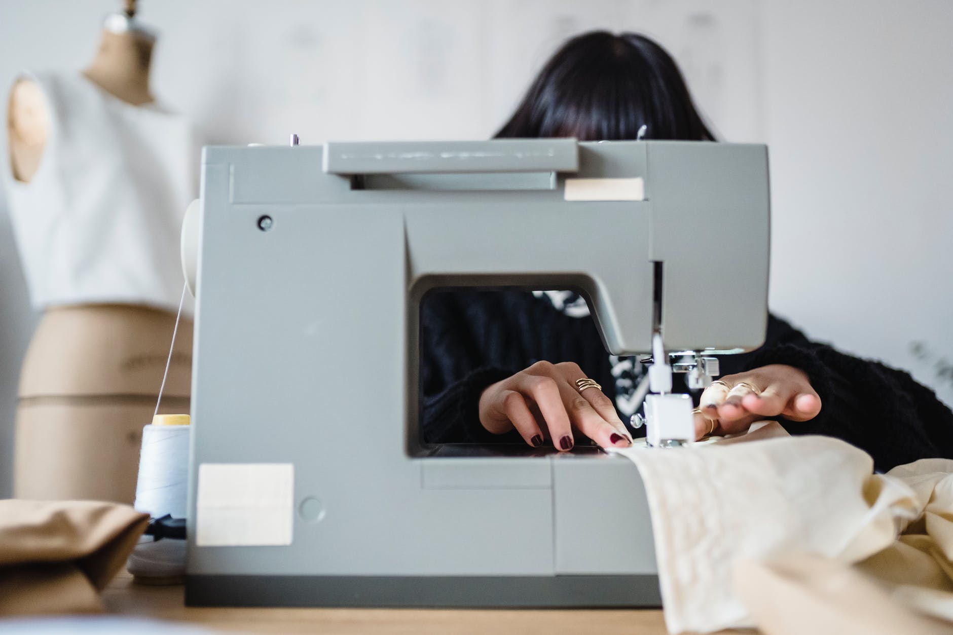 Sewing machine and hands moving white fabric.