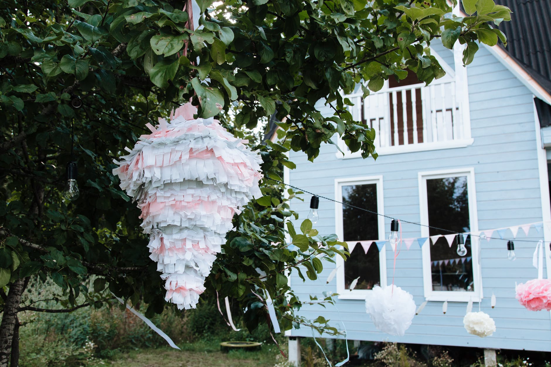 White and pink pinata hanging next to tree
