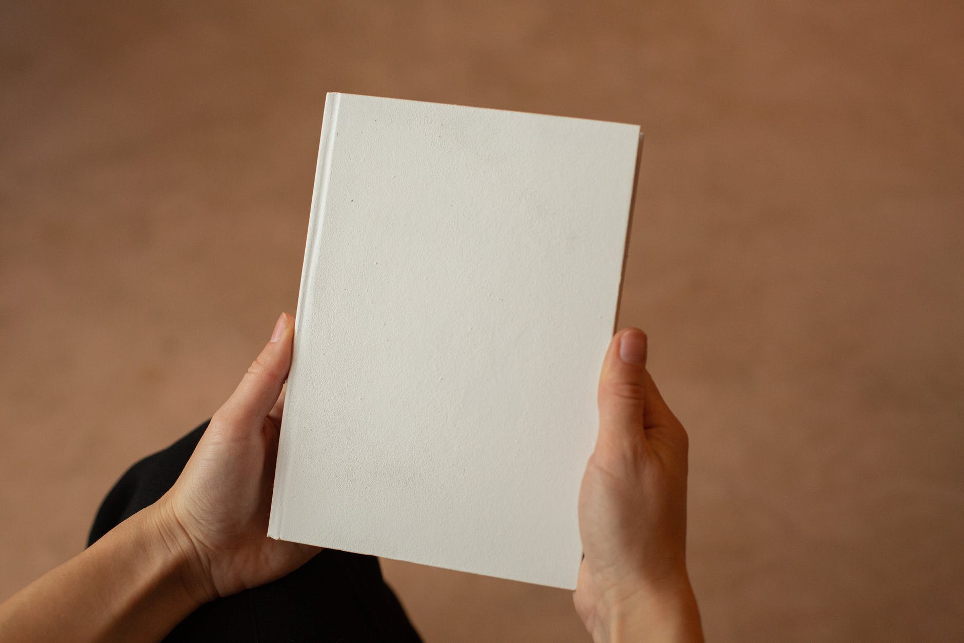 Book with no text held by two hands