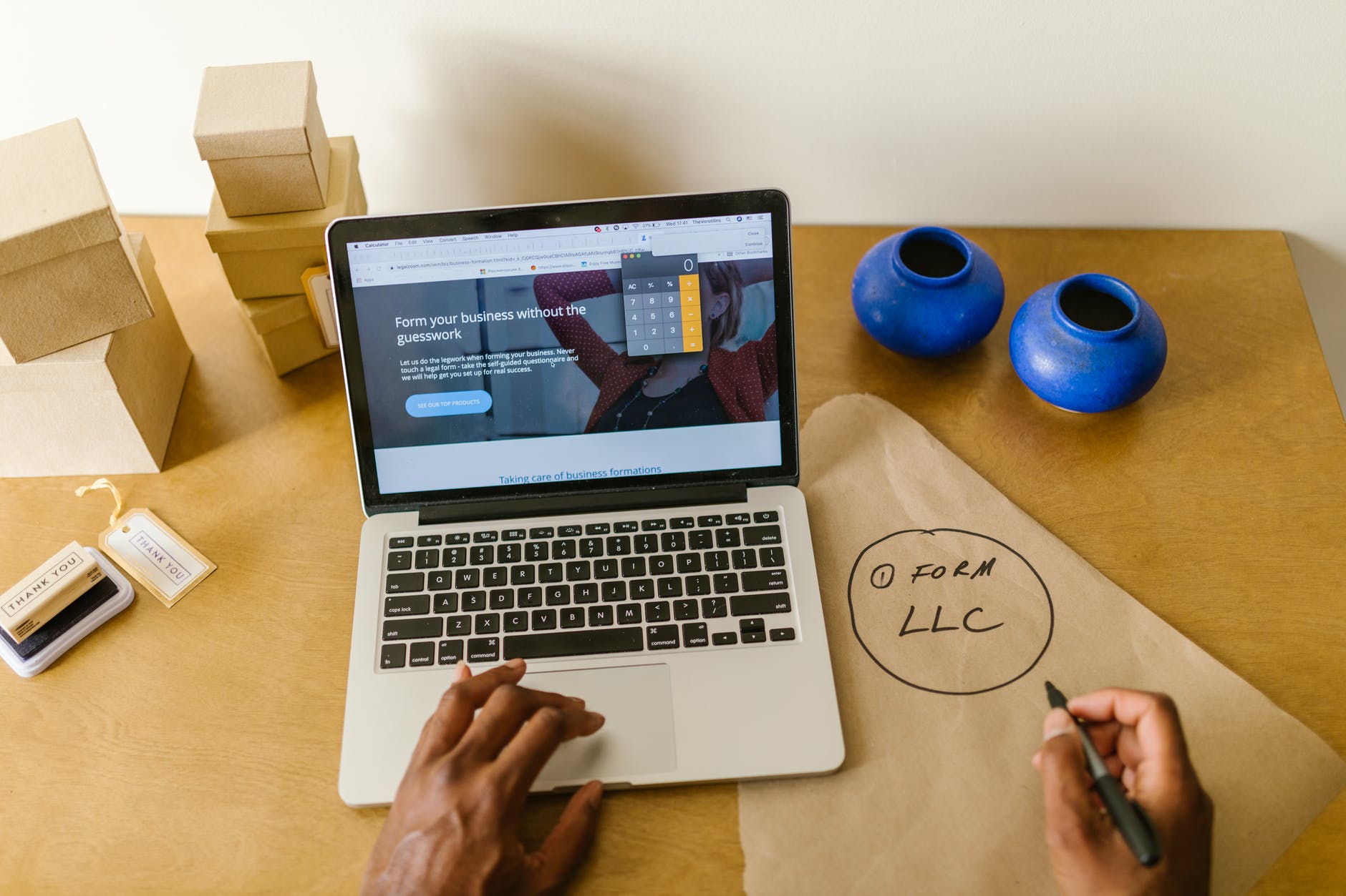 Hands on keyboard and holding market. Text on paper: "(1) FORM LLC"