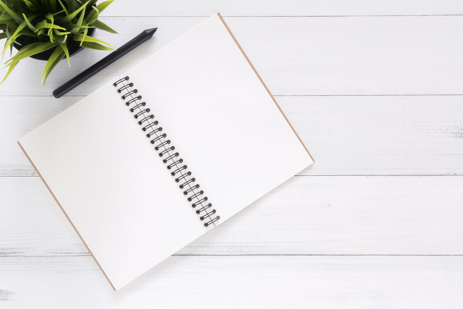 Notebook with blank pages and pen on white wooden table