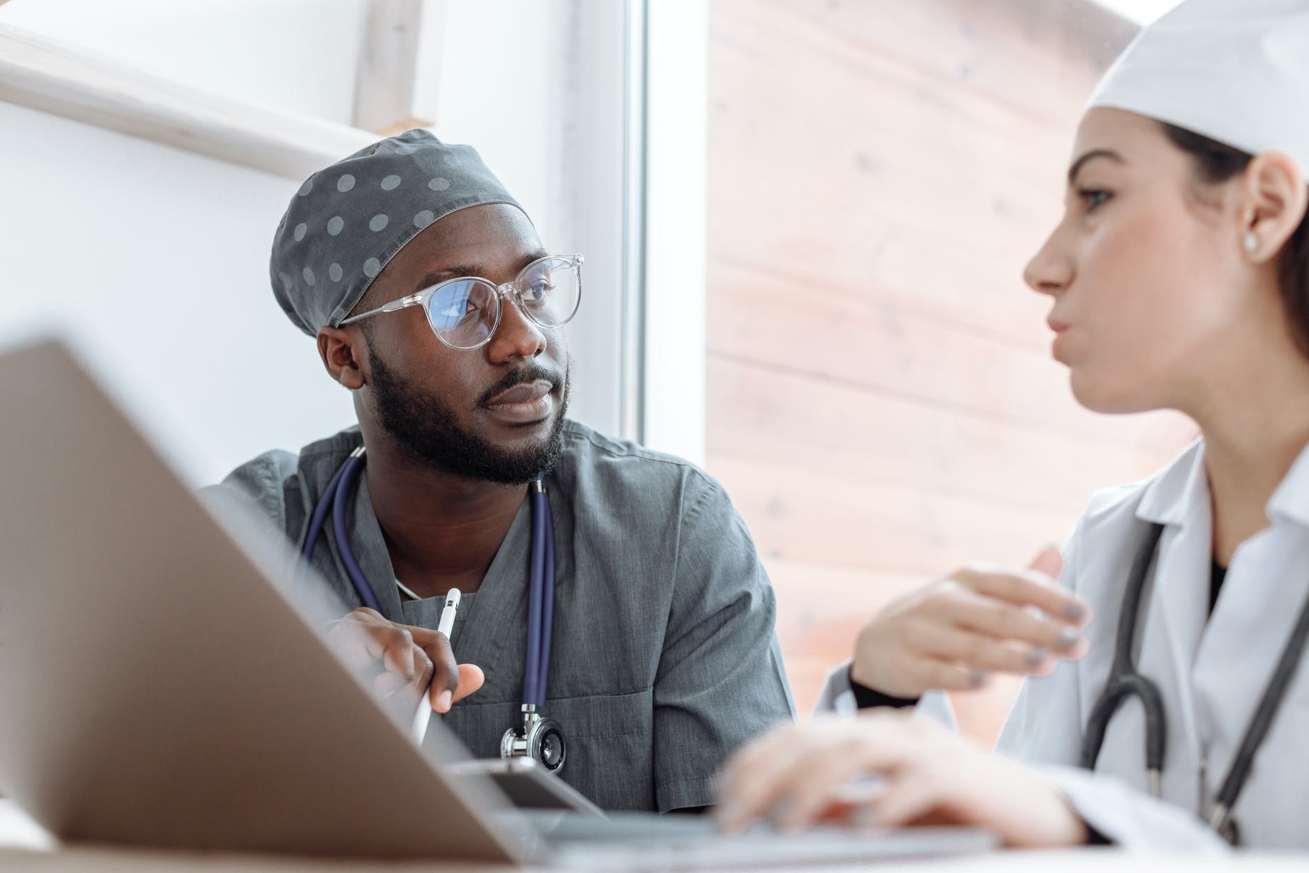 Black physician and white woman working in front of screen.