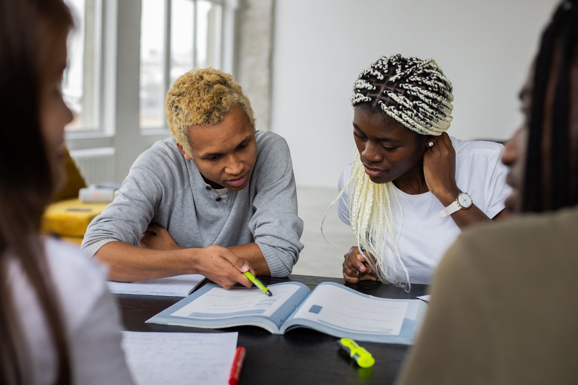 Two black students working at table. One is pointing to textbook.
