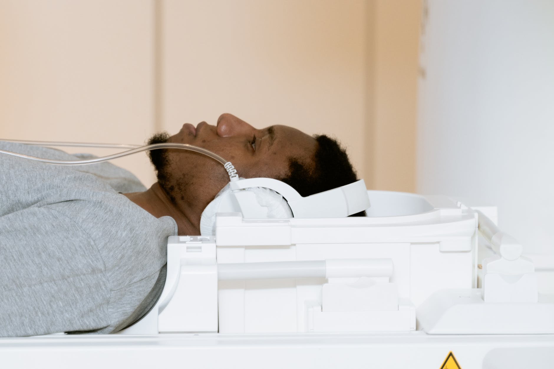 a patient in a hospital bed. A black man wearing a gray t-shirt.
