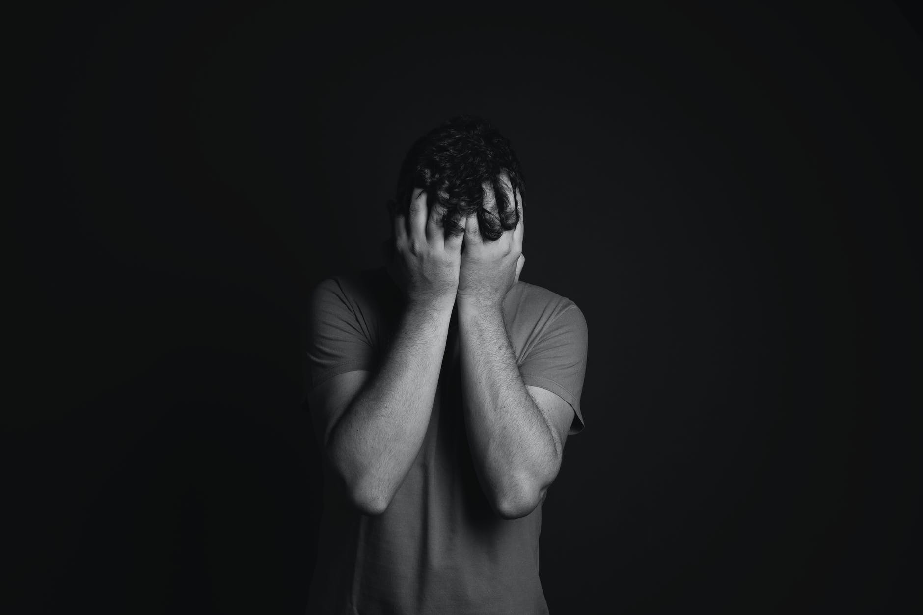 black and white photo of person covering face with hands