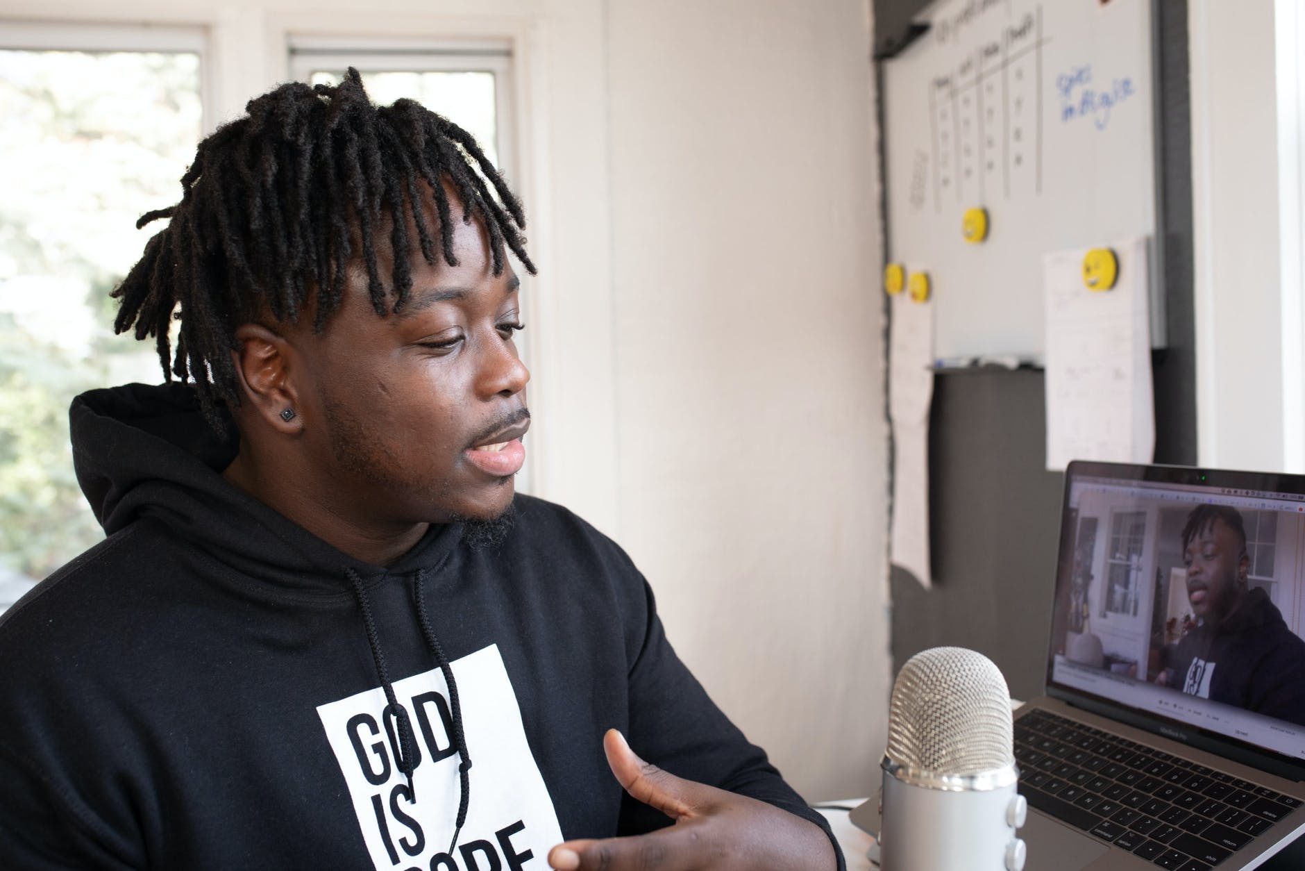 Black man recording podcast in front of laptop and microphone