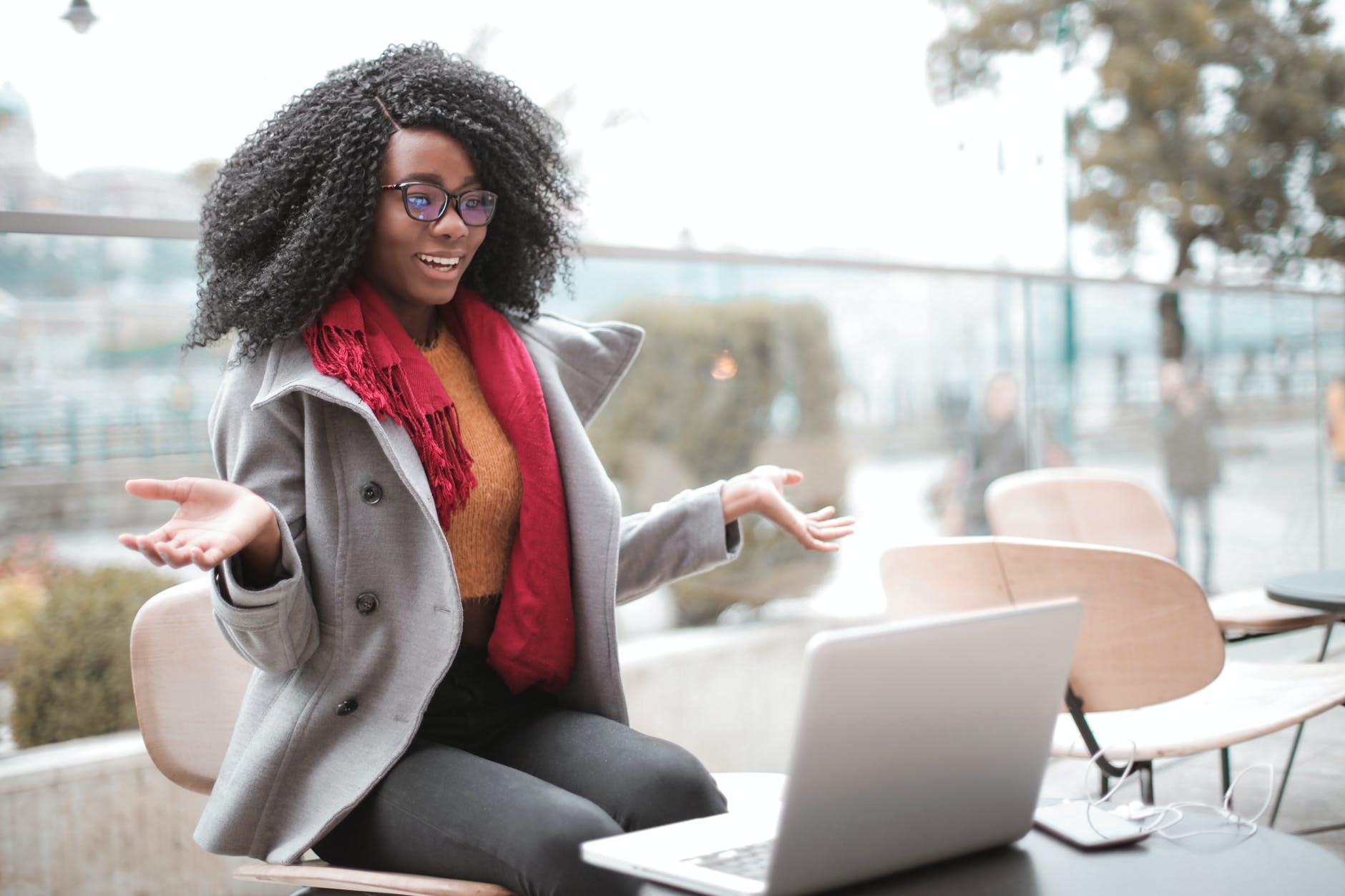 Black woman with curly hair outside smiling in front of laptop