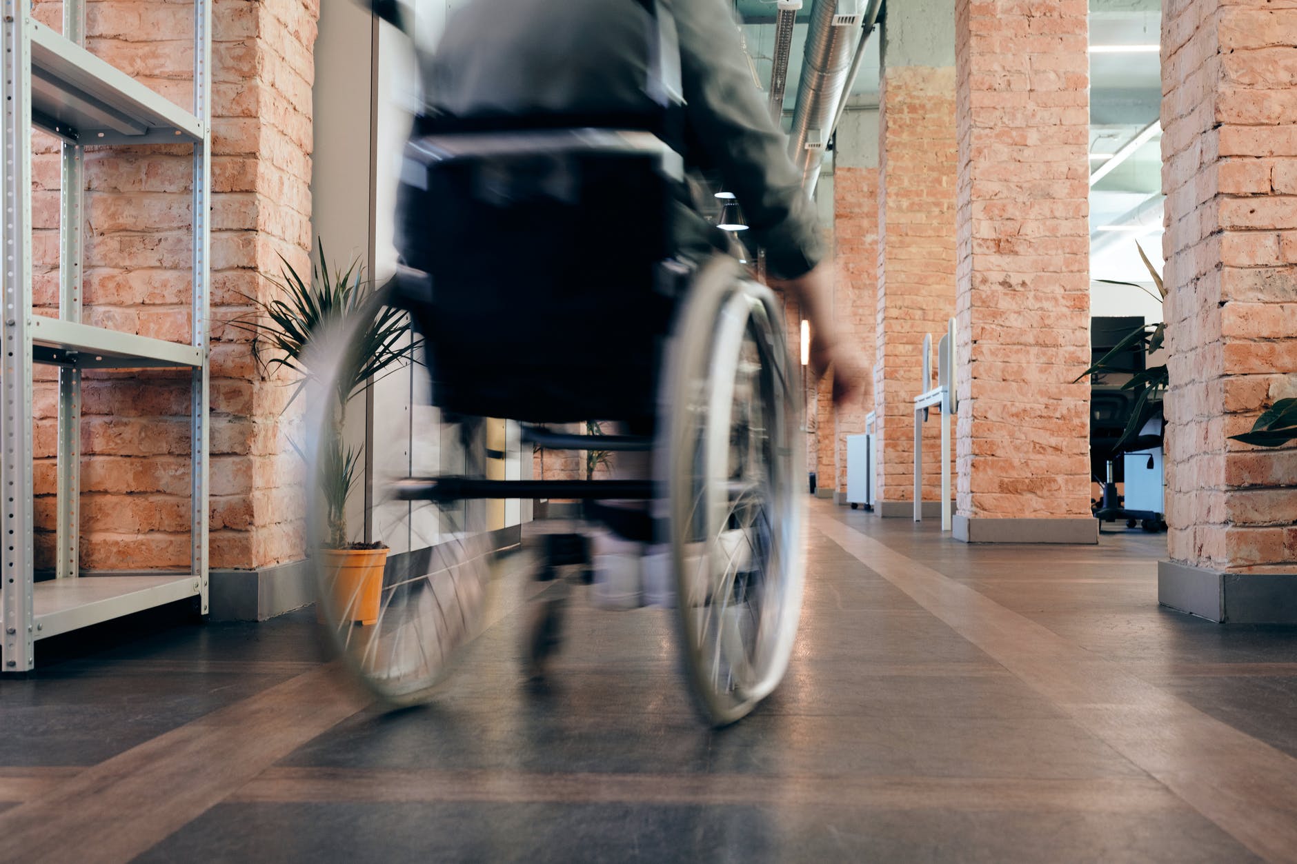 Wheelchair in hallway with brick columns.