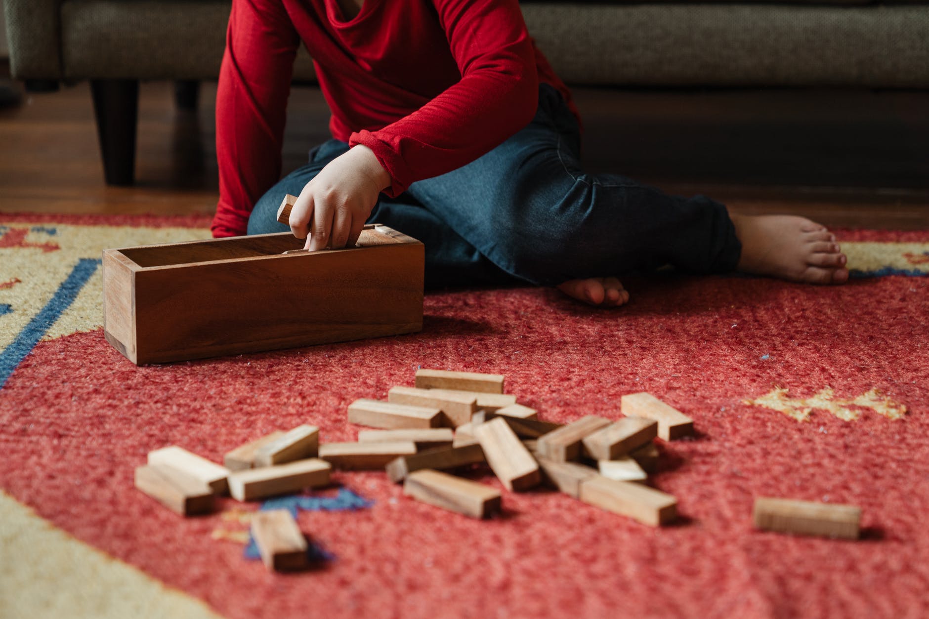 wood blocks on red carpet. Person wearing jeans in the background