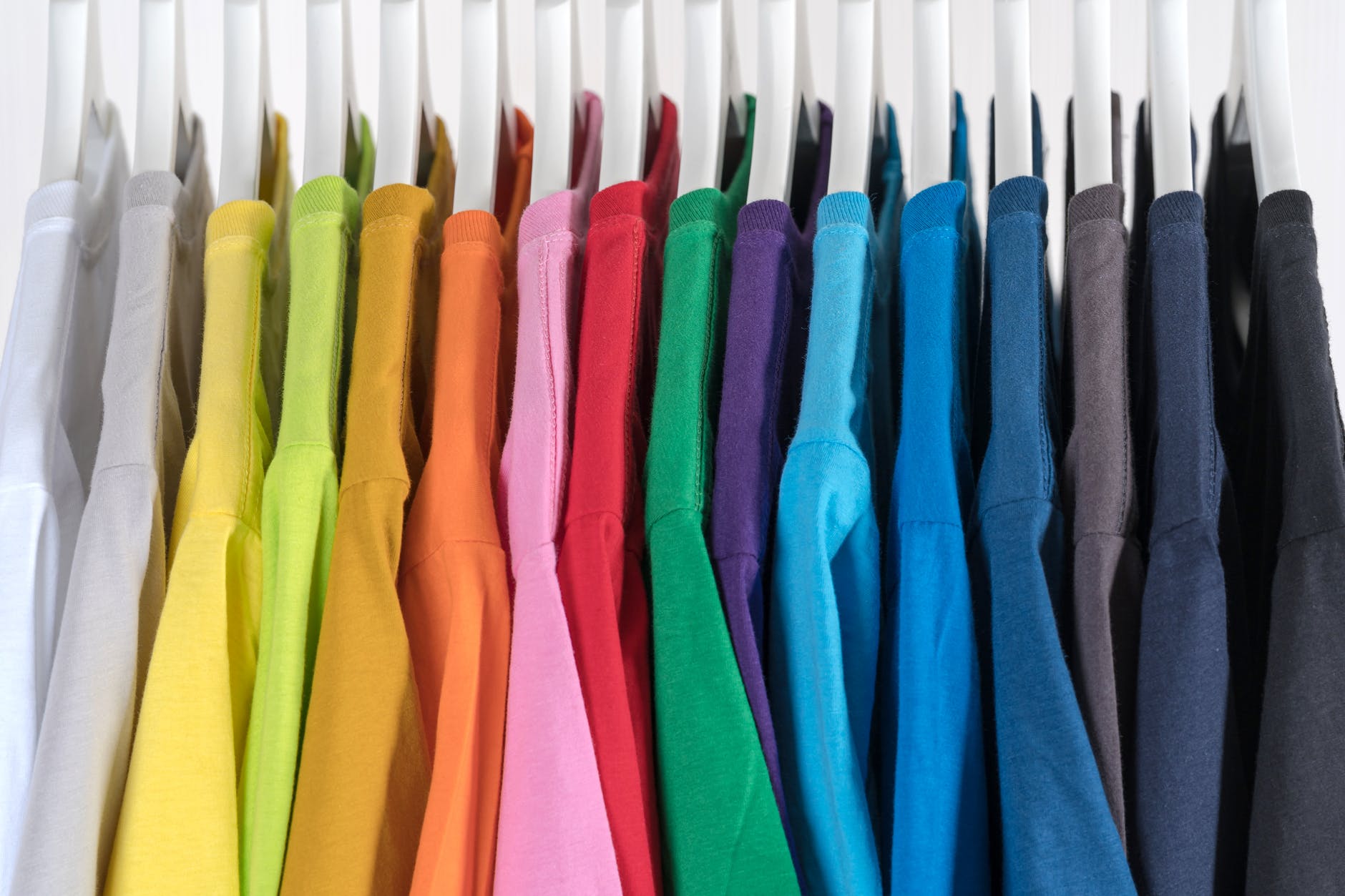 Multicolored polo shirts hanging from white hangers