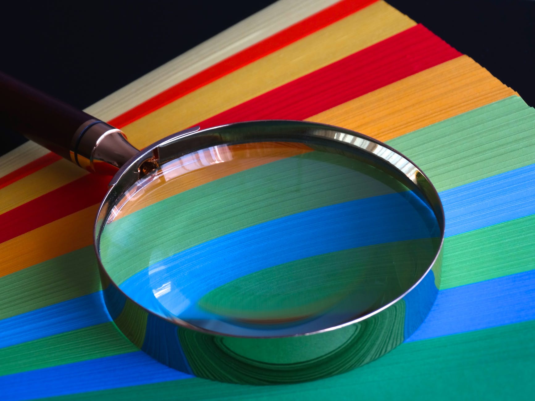 magnifying glass on yellow, green, ,blue, and red stripes.