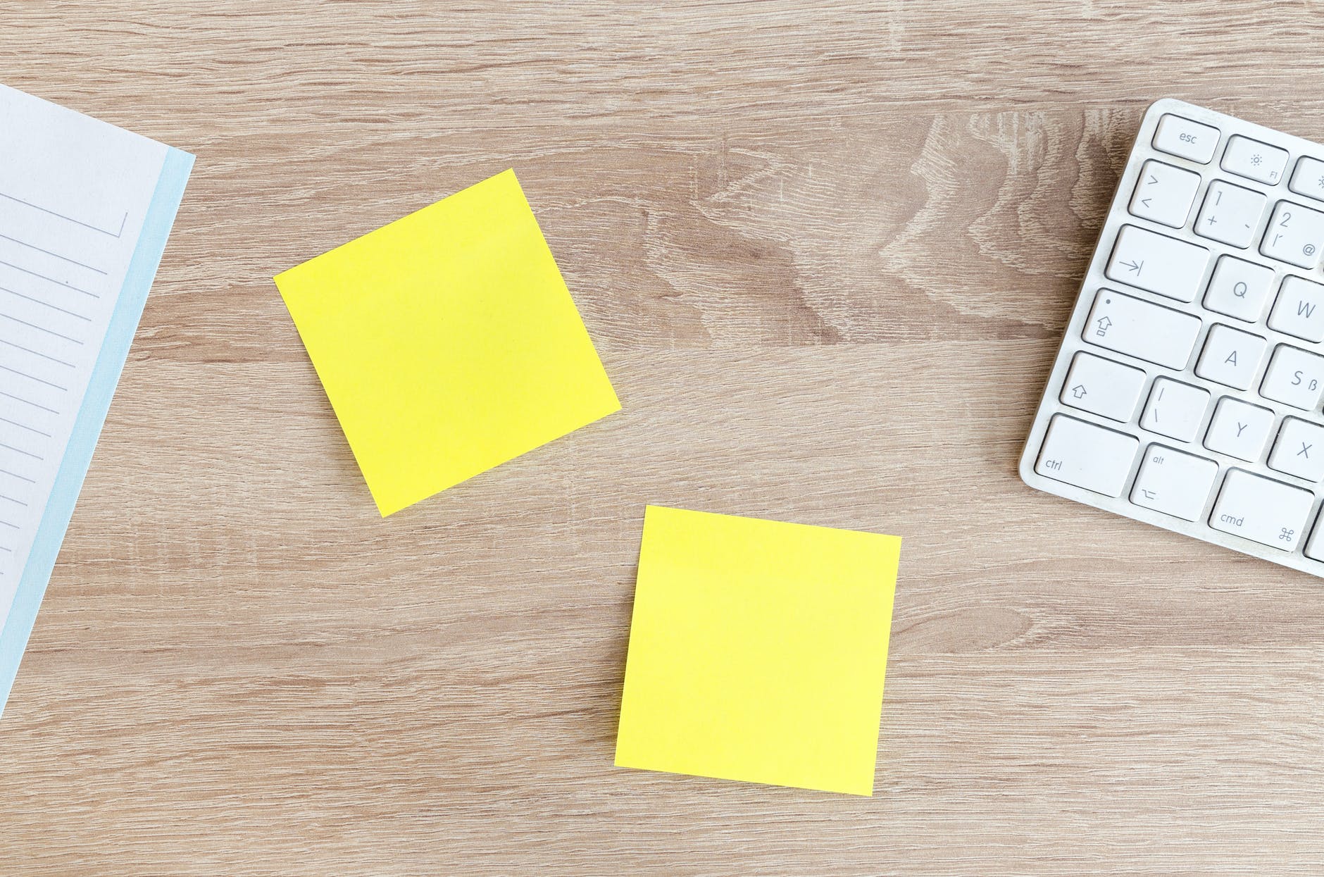 two yellow post its on wood desk with white keyboard