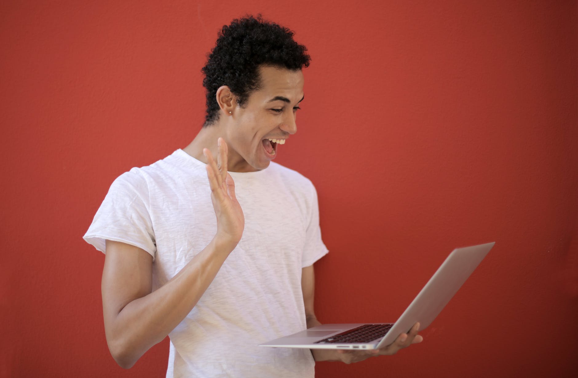 Person with curly black hair waiving at open laptop