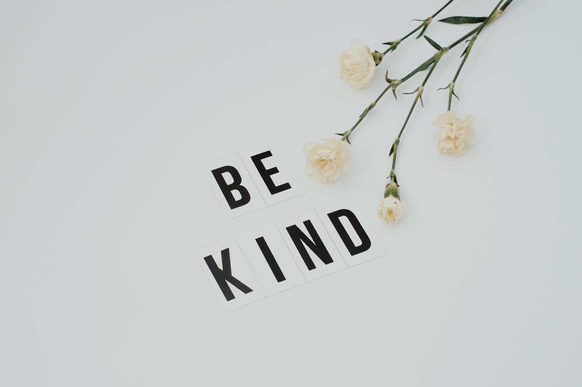 flowers on white background with black text "BE KIND"