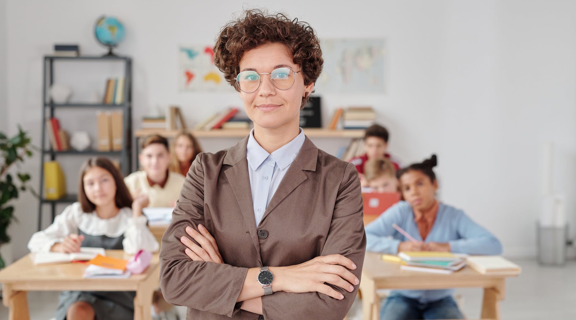 teacher with curly short hair and glasses in front of students