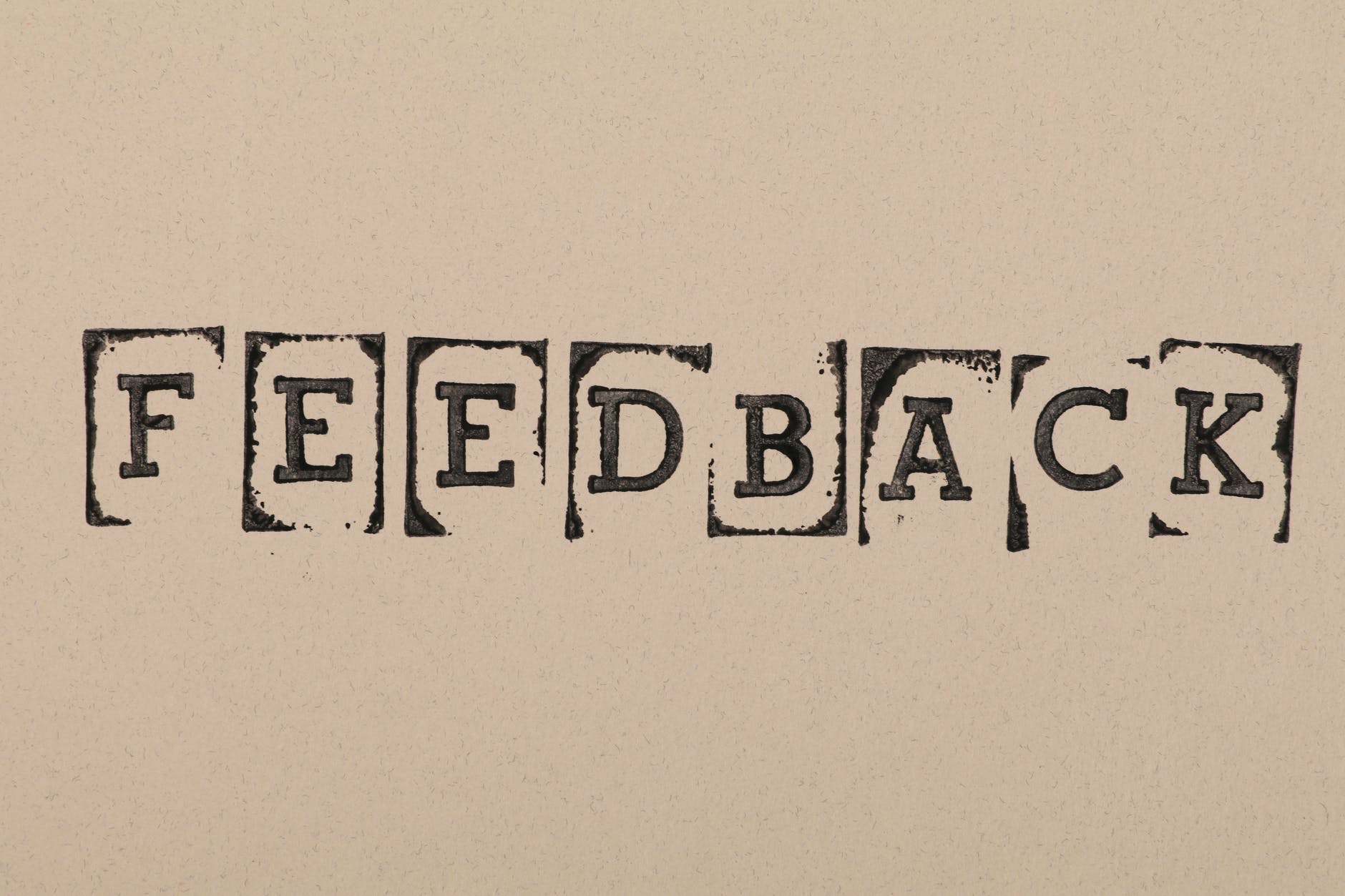 Black font spelling "FEEDBACK" on beige background