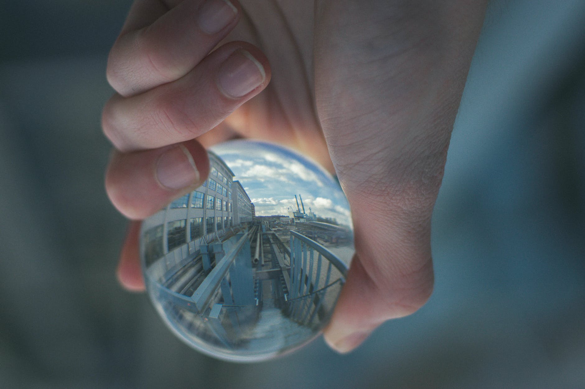 hand holding glass ball with upside down reflection of building