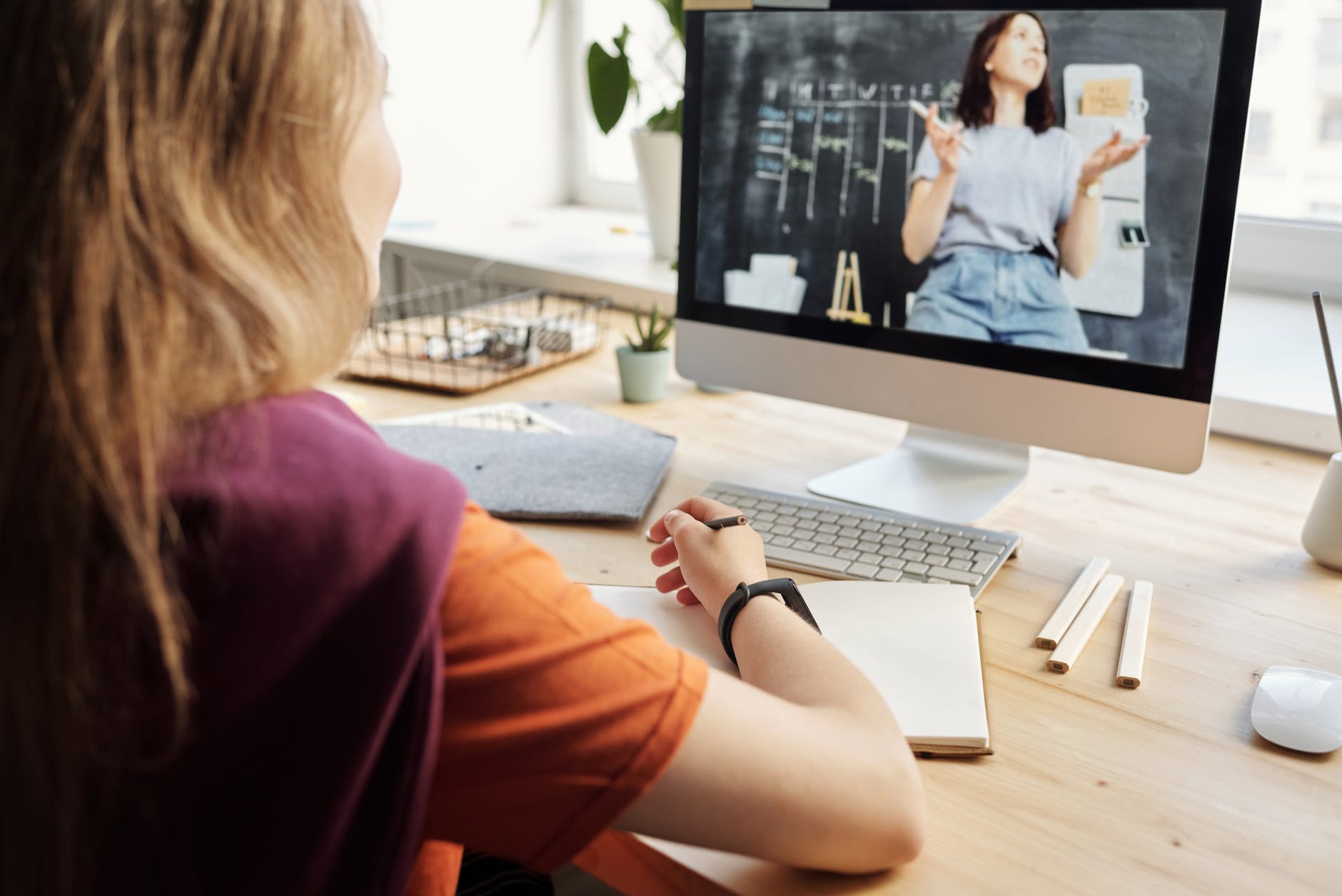 girl seated at desk watching teacher on screen