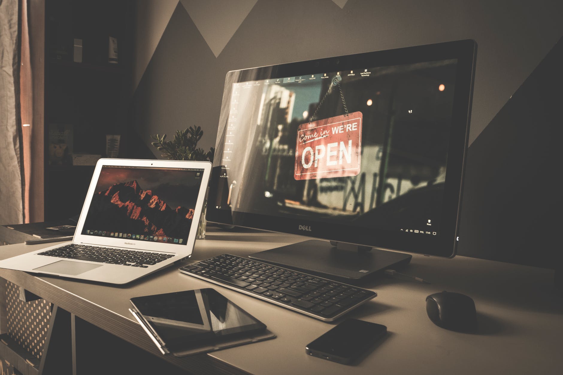 laptop and desktop on table along with keyboard, mouse, and tablet