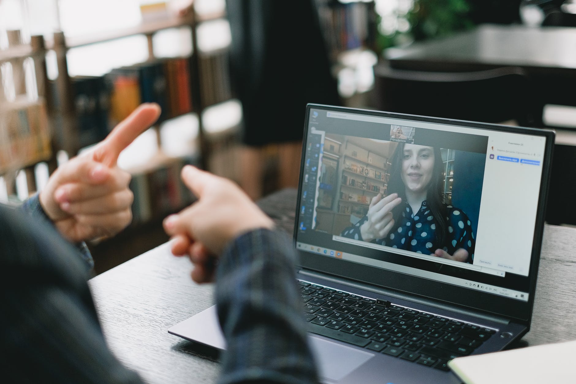 two people one on laptop screen and the other signing in front of laptop.