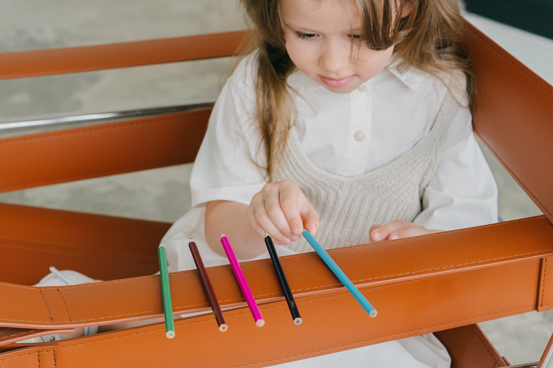 Girl lining up five colored pencils