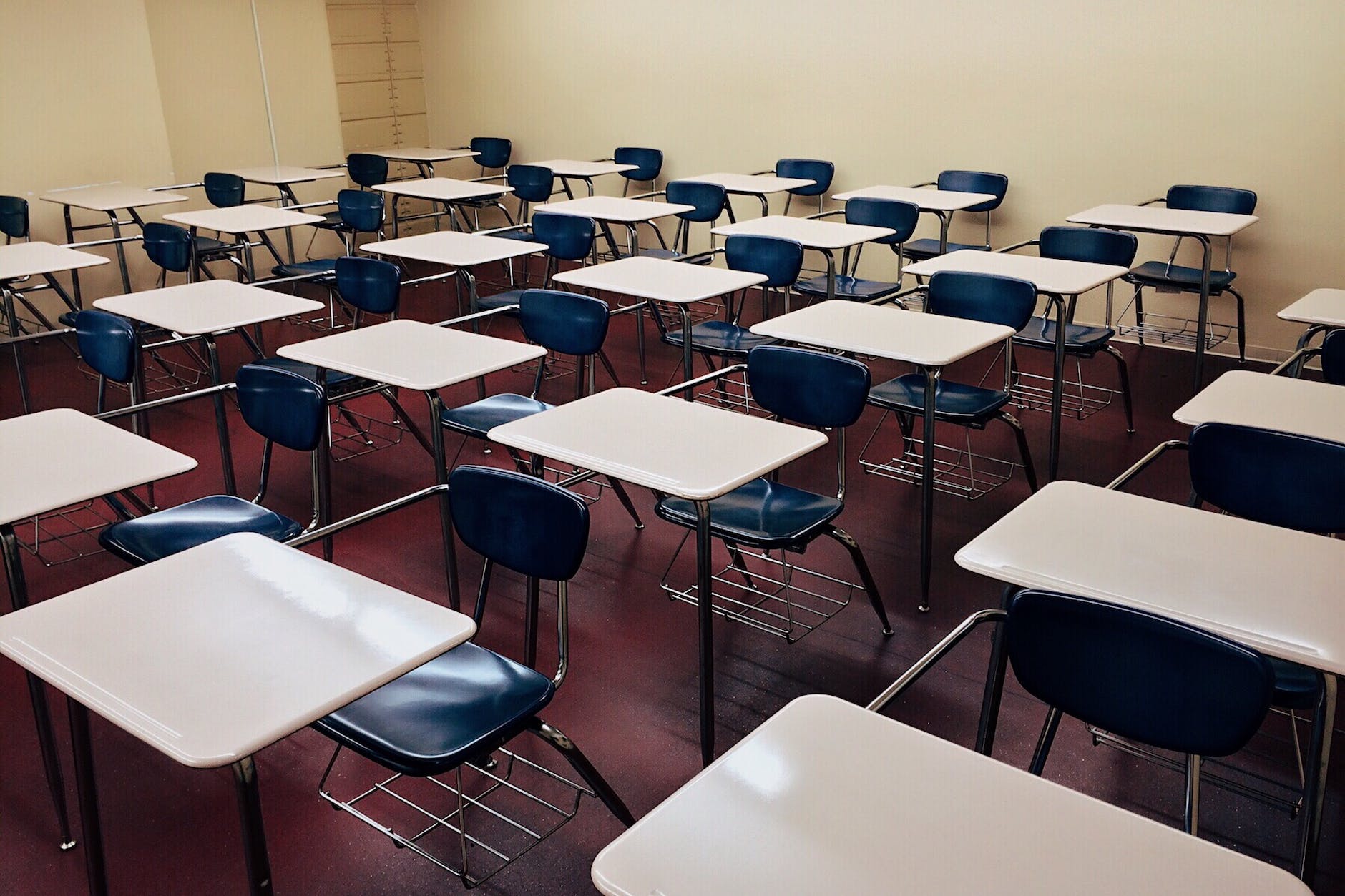 Rows of individual desks in empty classroom.