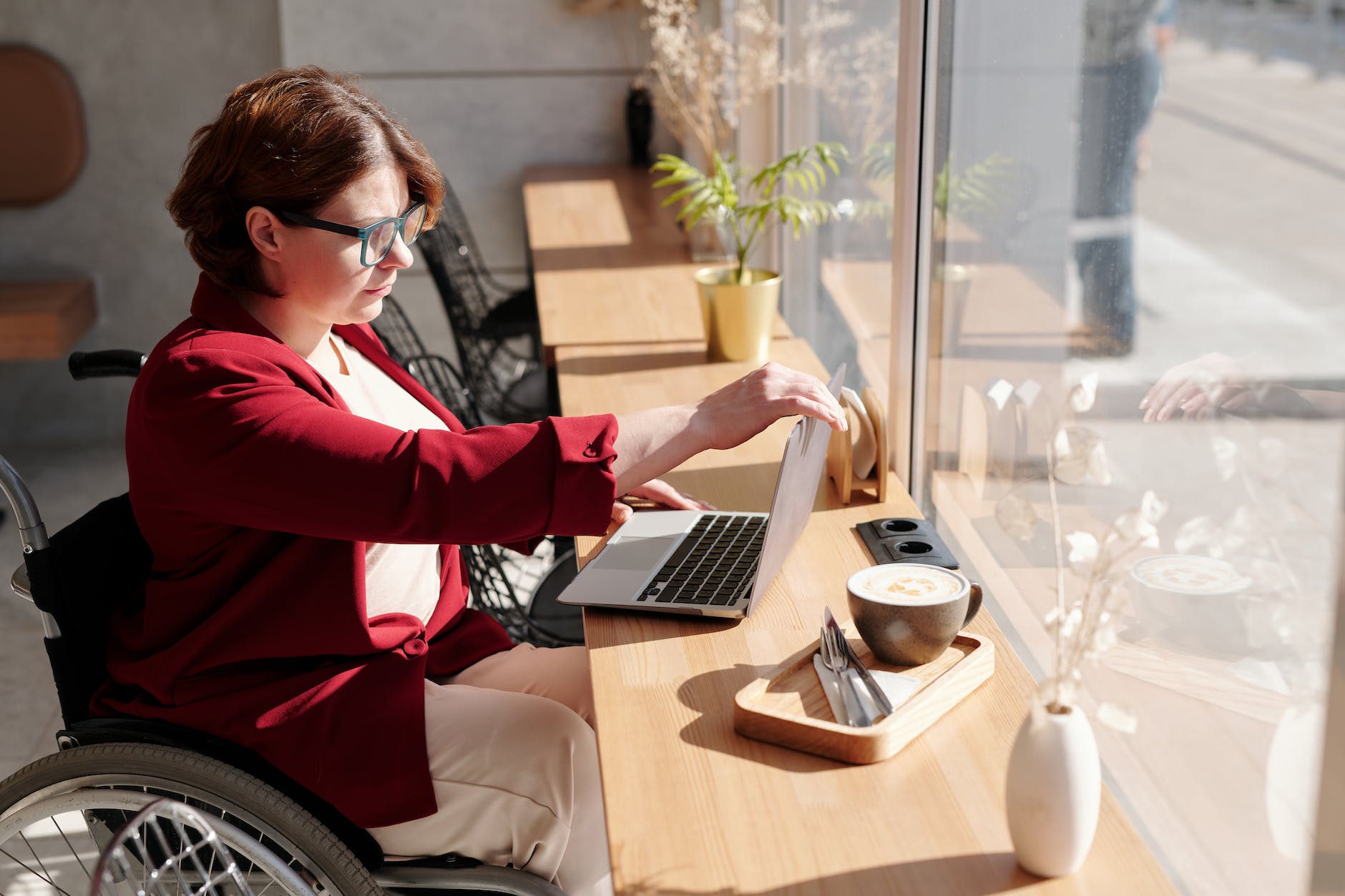 woman in wheelchair at table next to window
