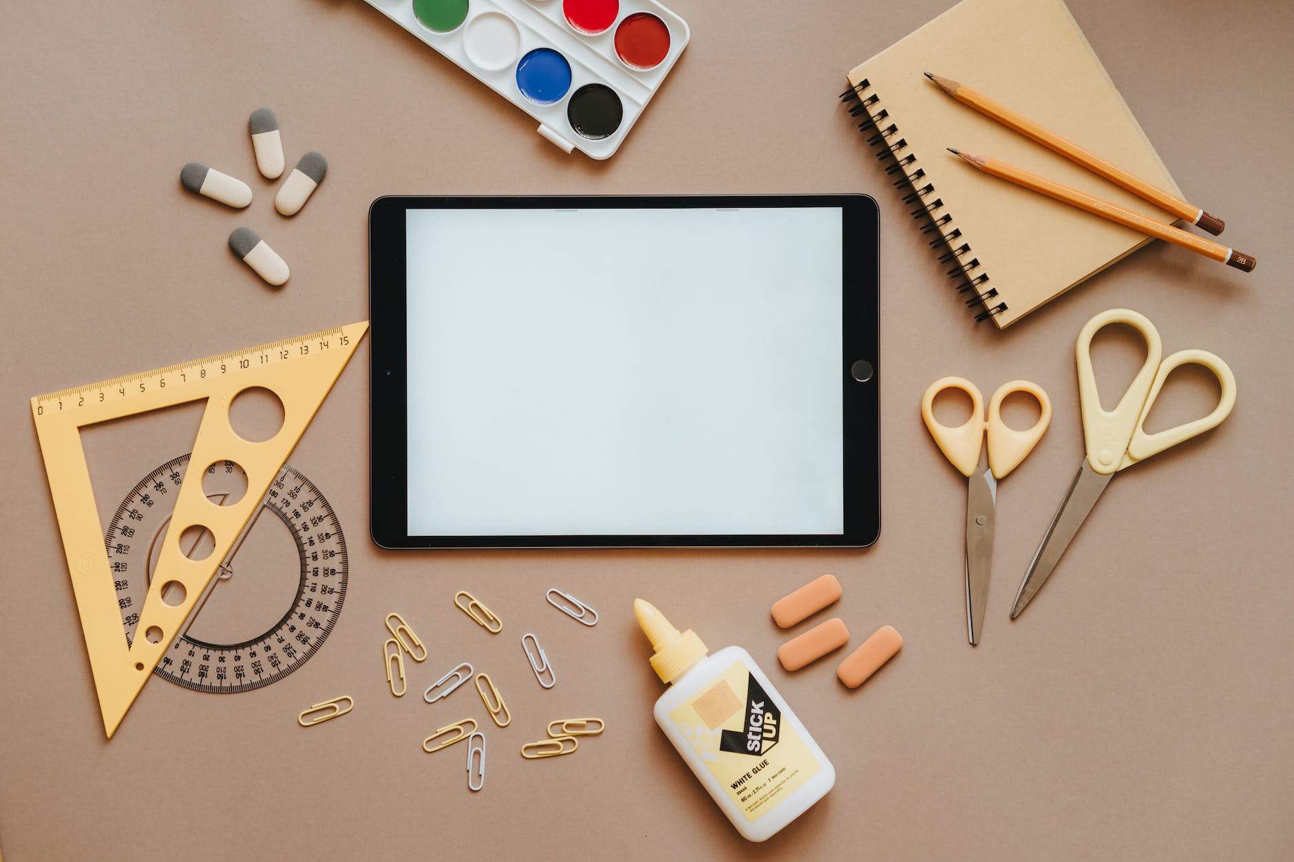an iPad, two pairs of scissors, clips, paper, and watercolors