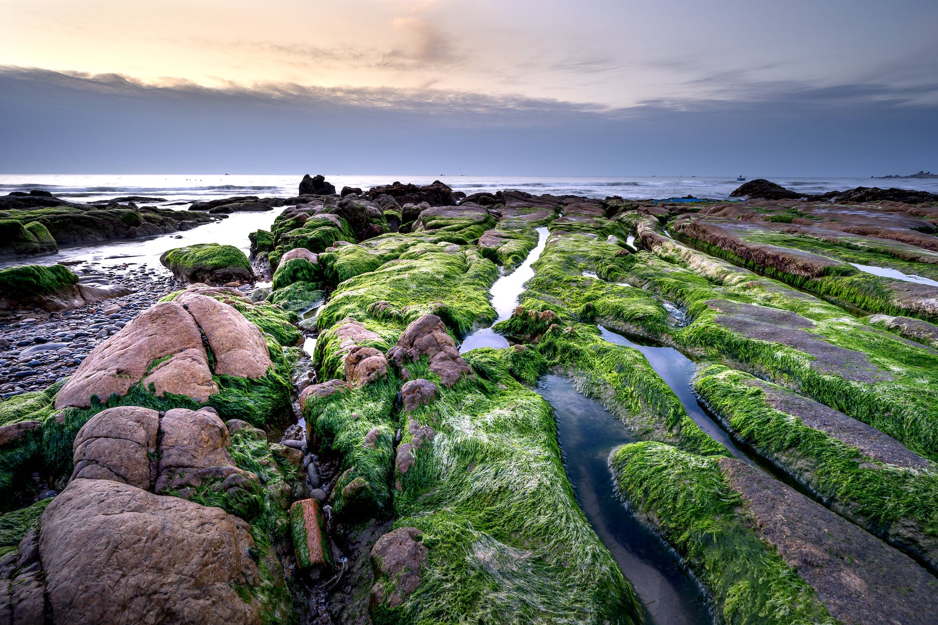 landscape with rocs with green moss, water, and clouds