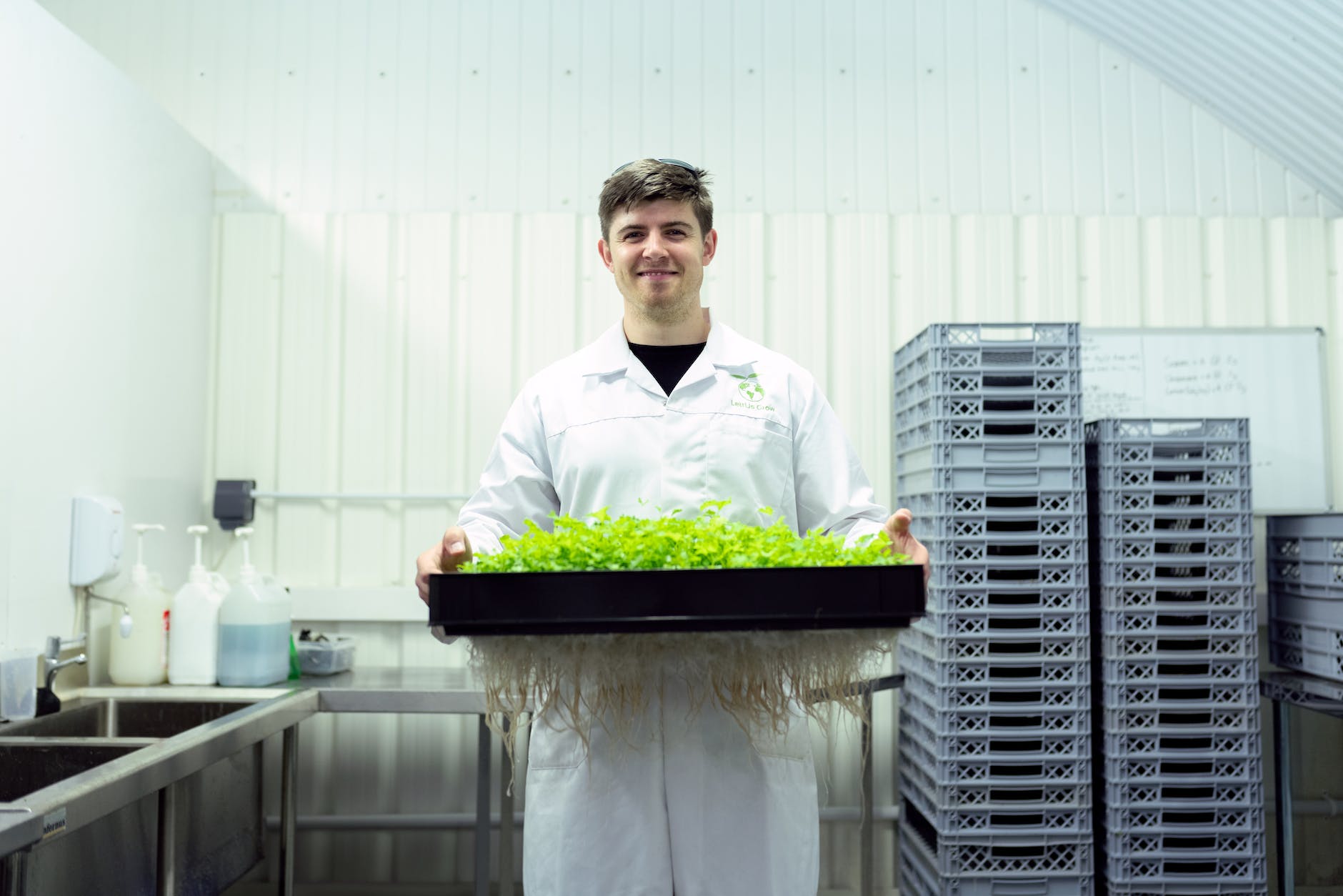 man wearing lab coat and holding tray with plants