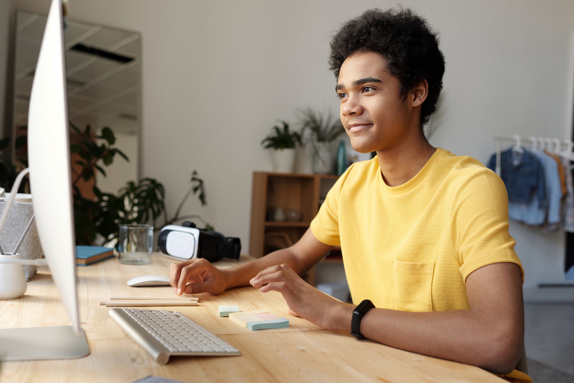 Black man with curly hair staring at desktop computer screen.