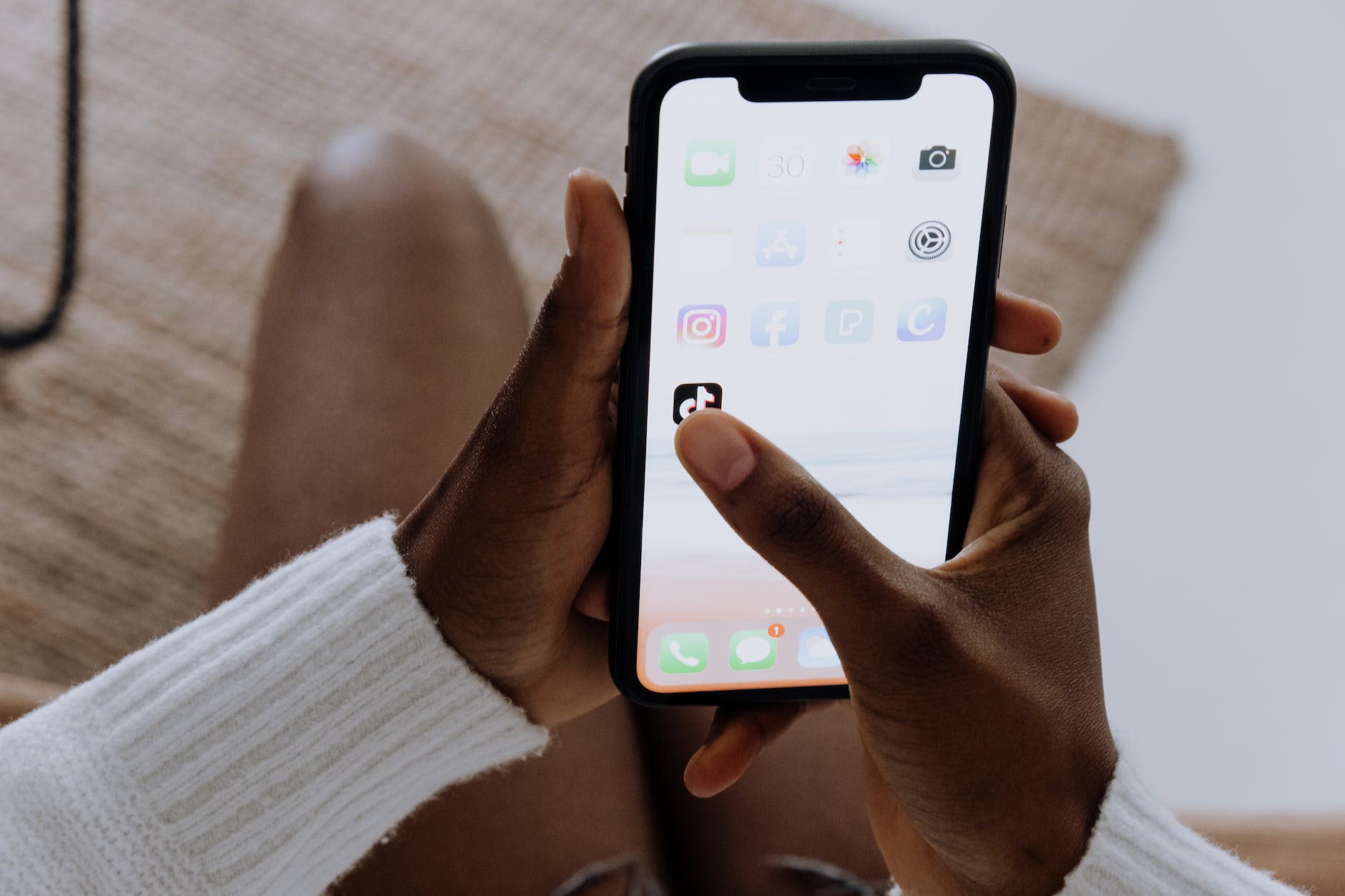 Black hands holding phone with TikTok app