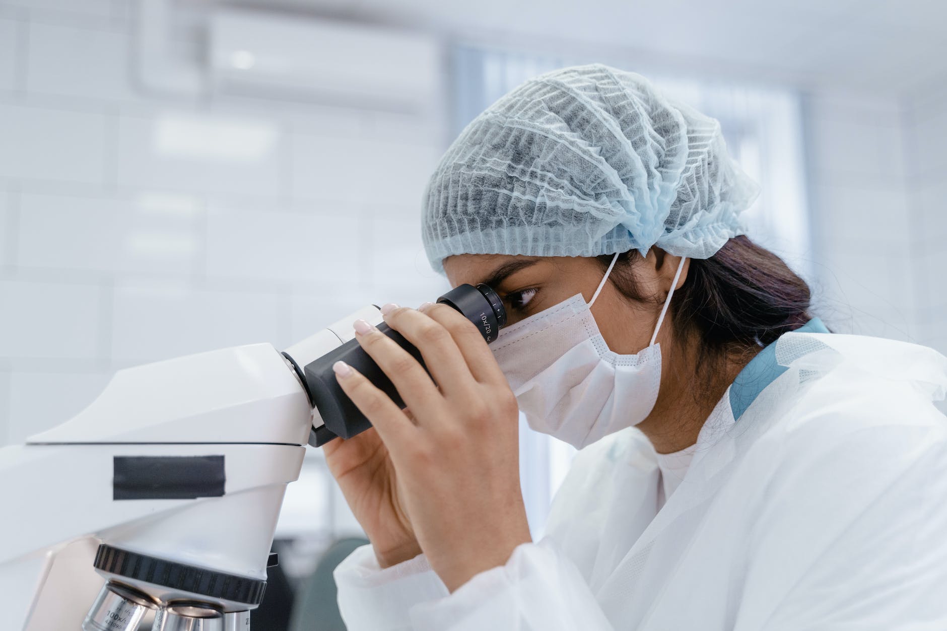 A female lab technician with hair wig and using a microscope. 