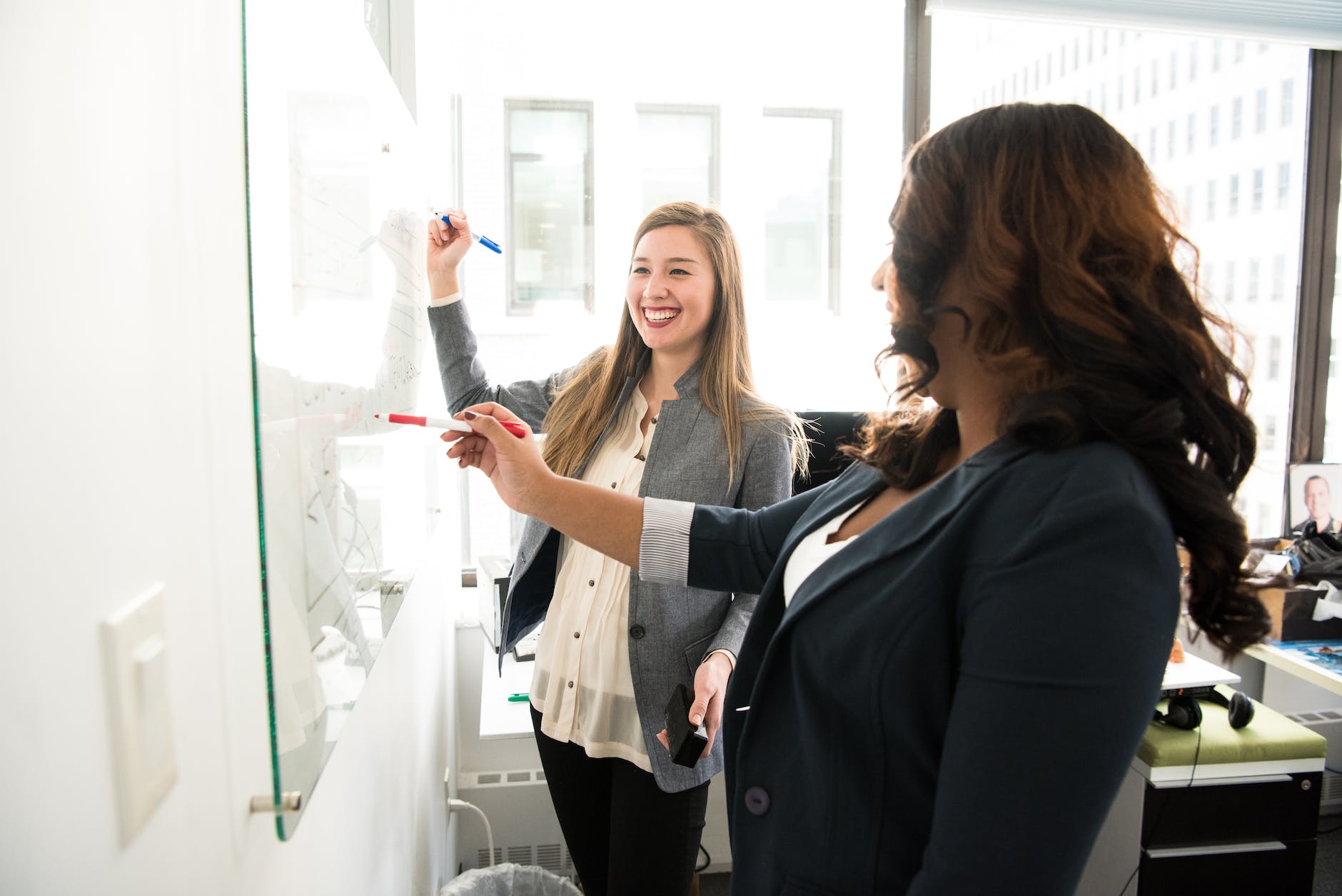Two women in front of dry-erase board.