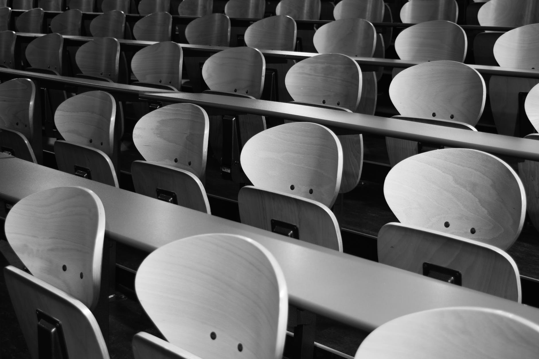 empty rows of seats in a lecture hall. Seats have rounded white backrests