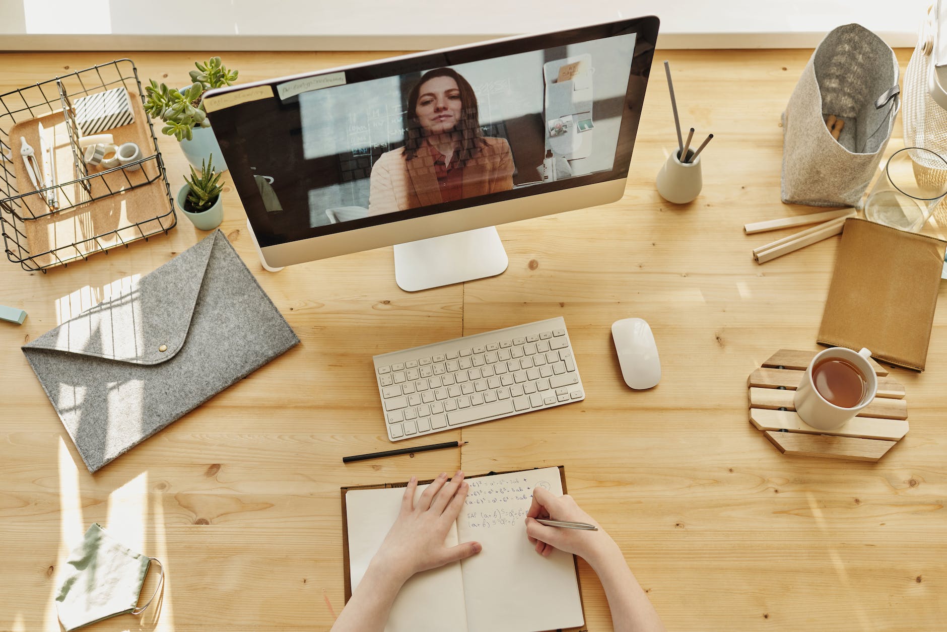 top down view of desktop and keyboard with videoconference and woman on the screen