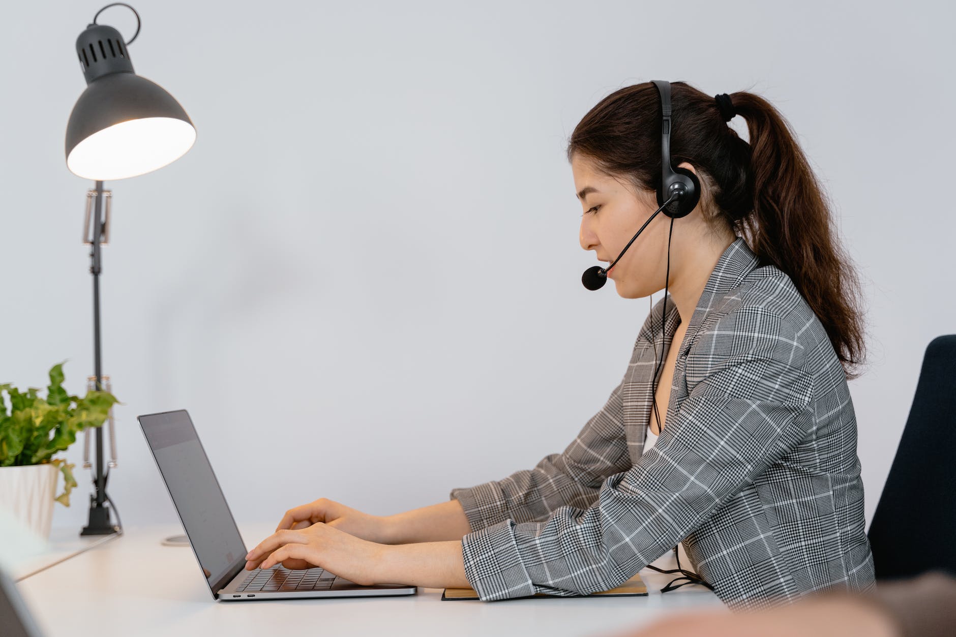 woman with long hair in pony tail working at desk and wearing headphones