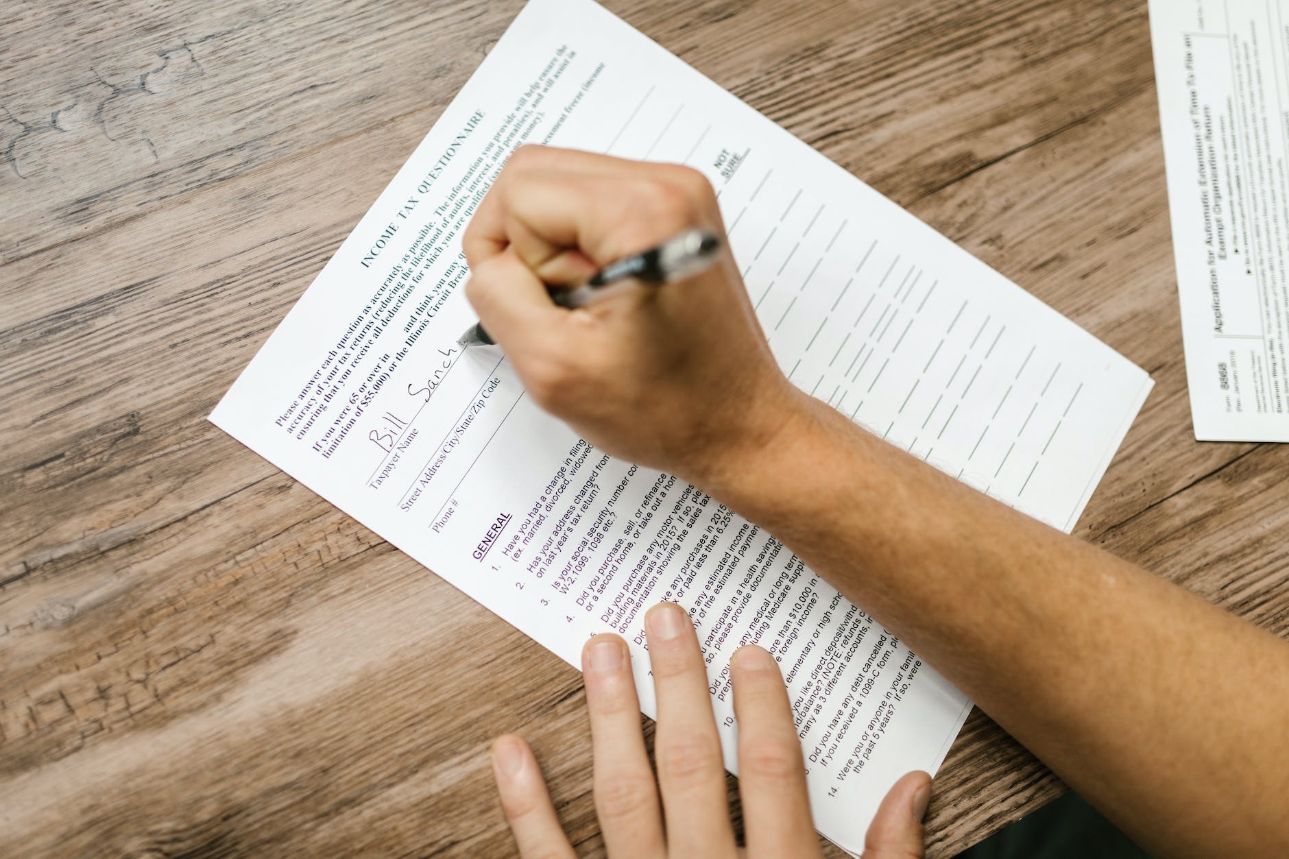 Hand holding pen and completing questionnaire