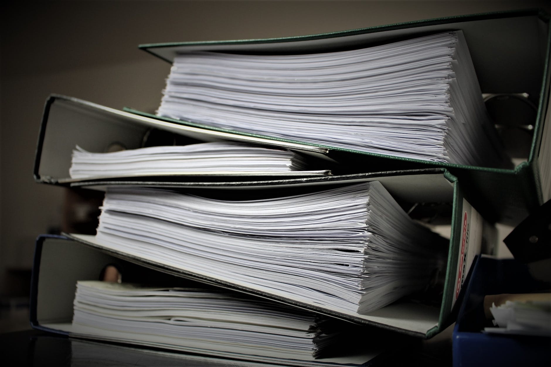 a pile of folders with white pages. Four thick binders
