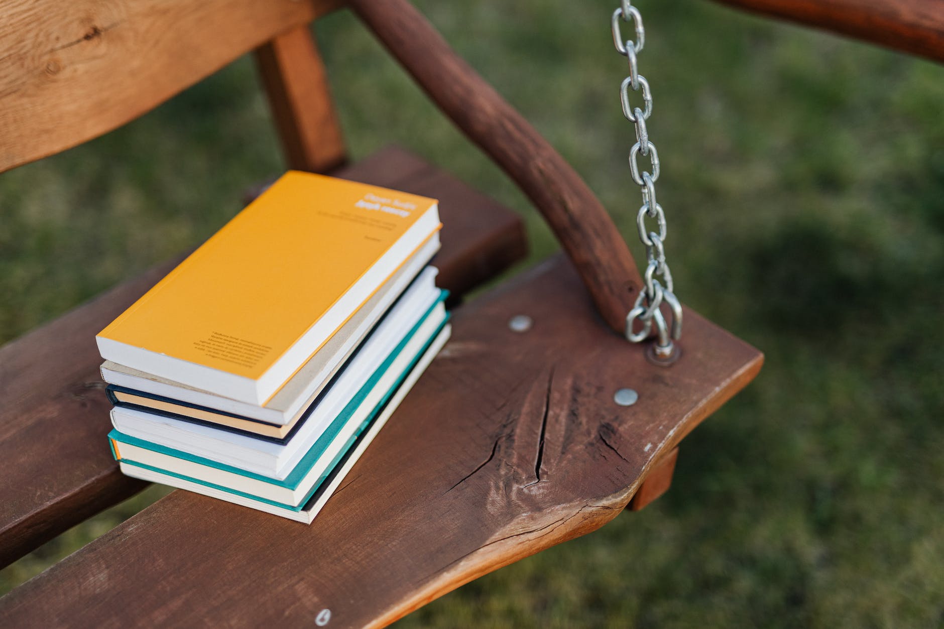 Stack of books placed on the seat of a wooden swing