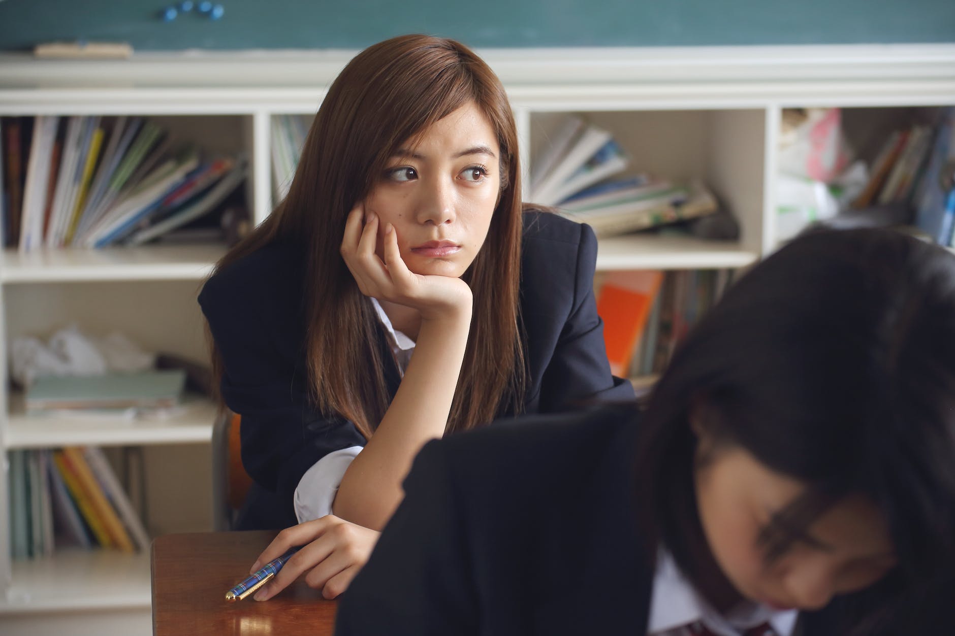 woman holding chin sitting in classroom