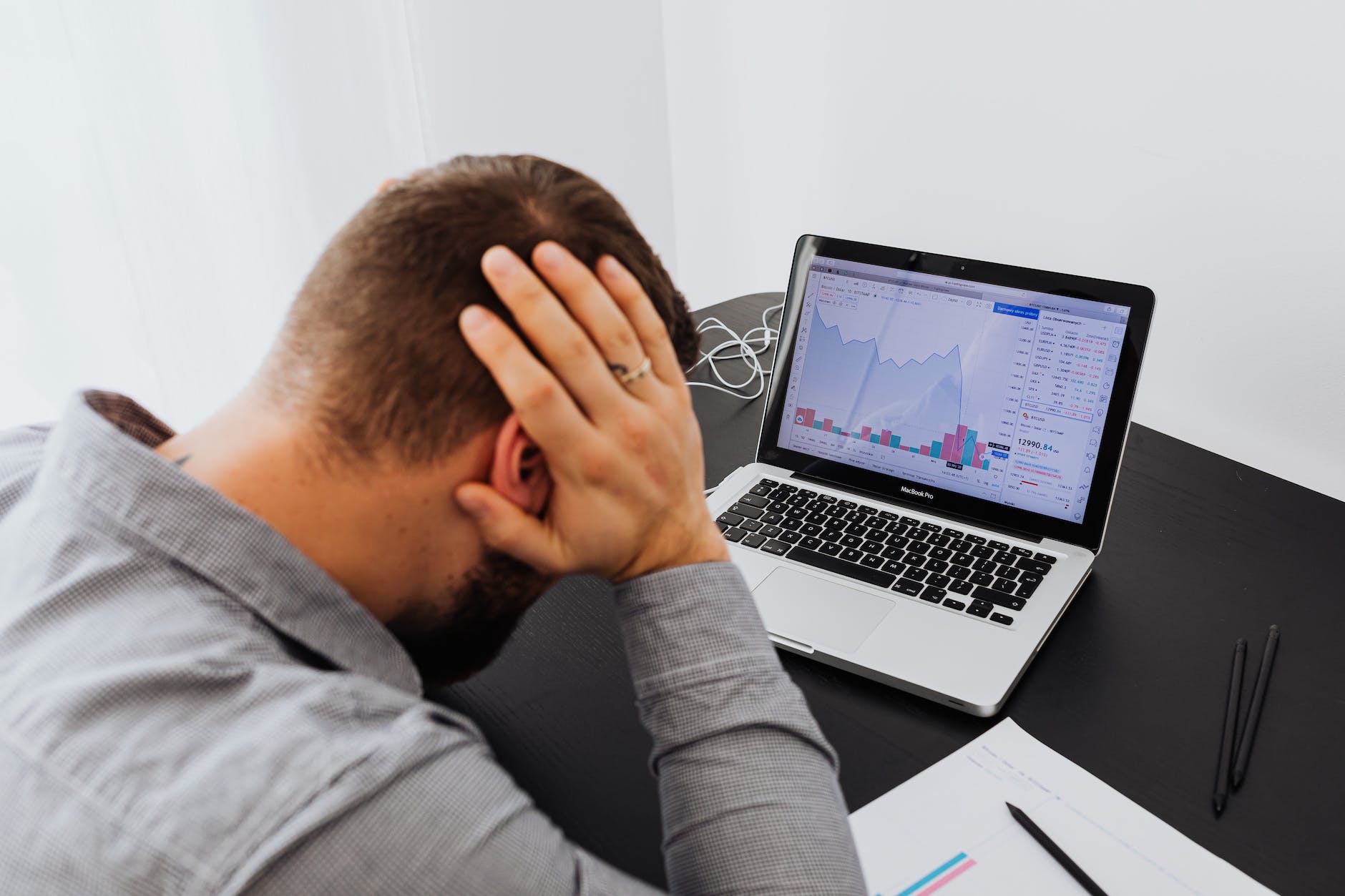 man with laptop on desk frustrated by data