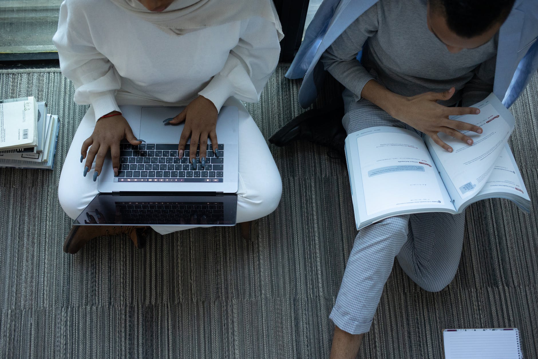 Two students reading and working on a laptop, respectively.