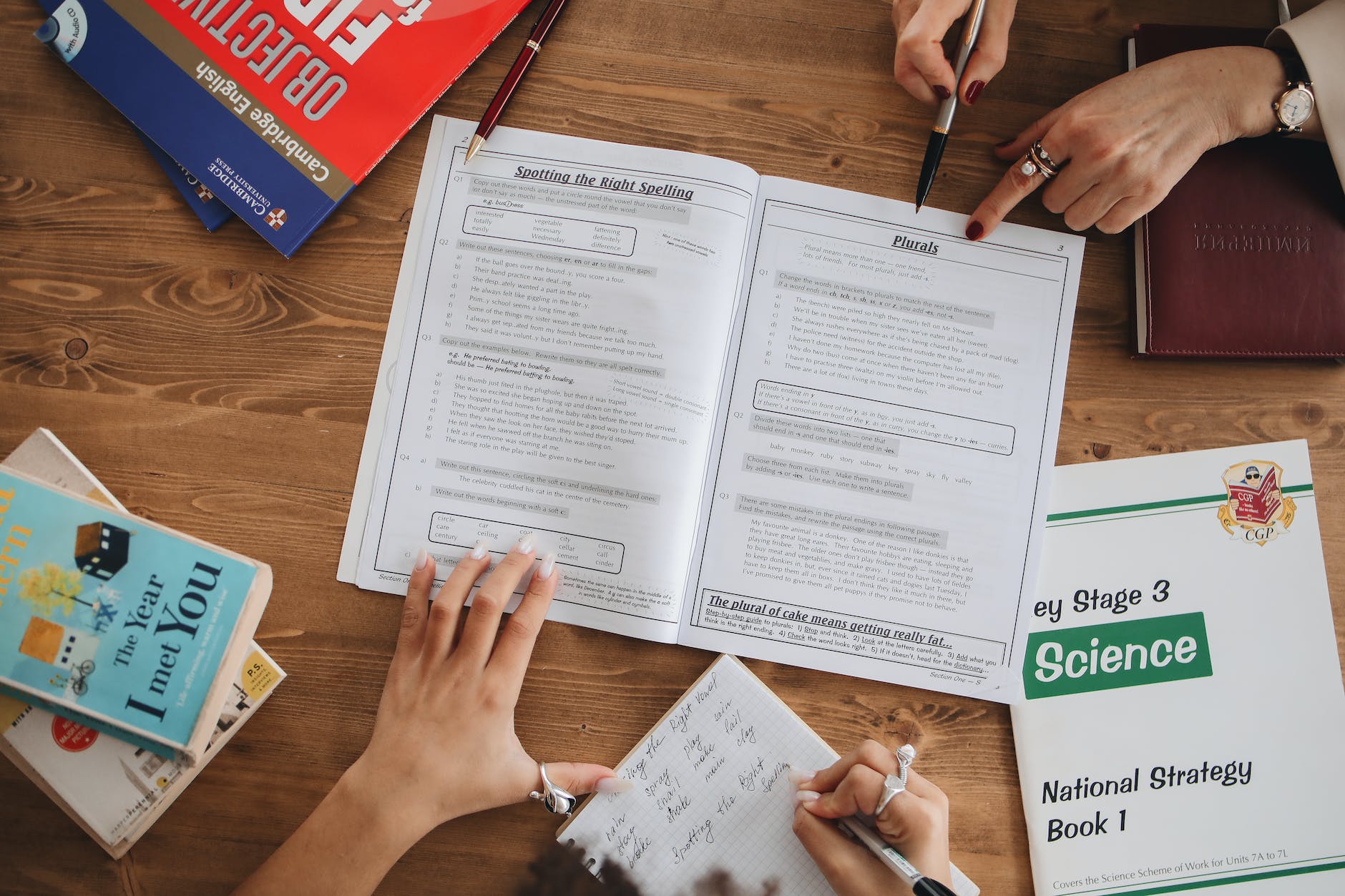 top down view of open textbook/workbook and hands holding the texts