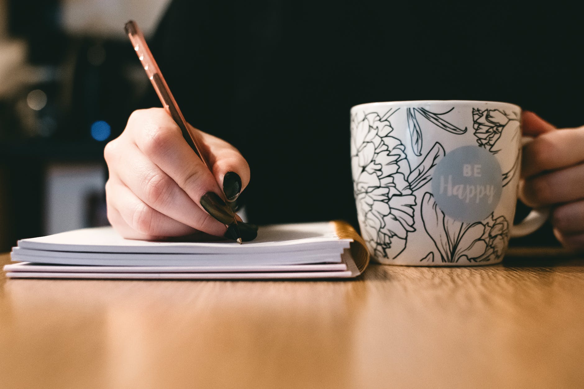 Person holding white be happy mug and pen