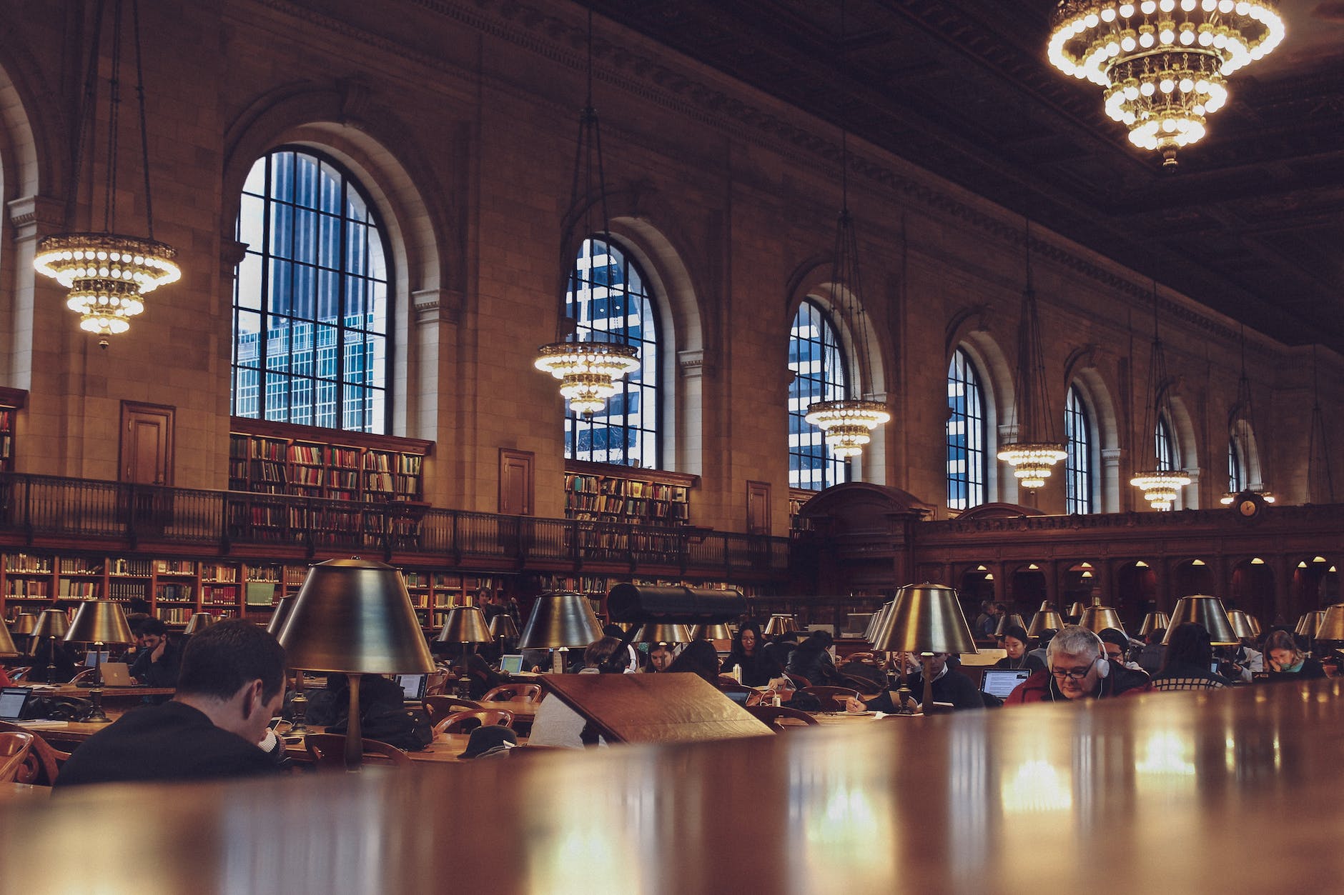 photo of people in dark library with chandeliers