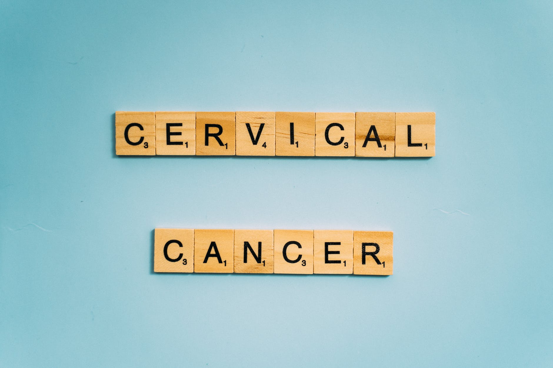 scrabble tiles on a light blue surface spelling CERVICAL CANCER