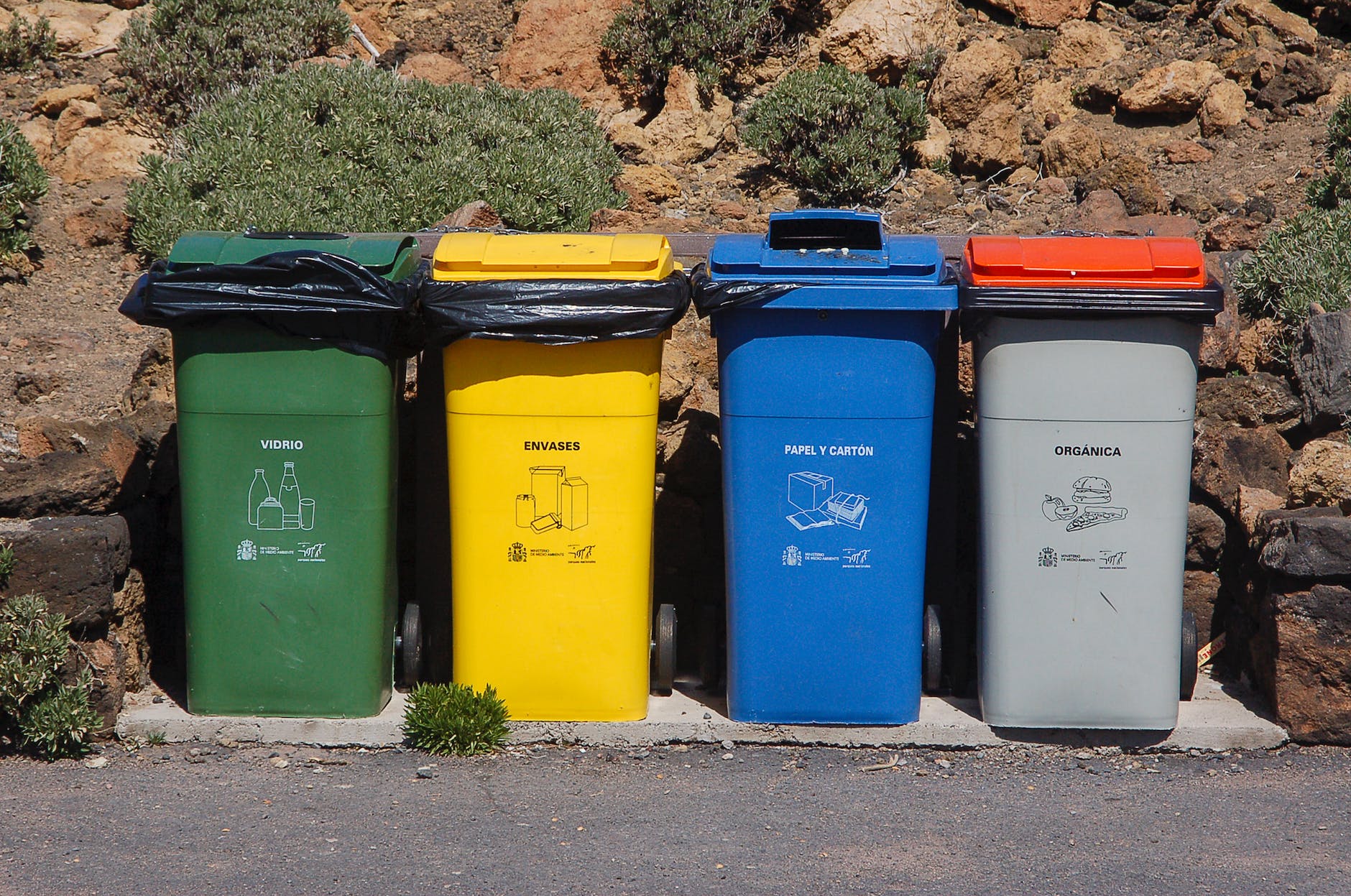 four containers for trash and recycling: green, yellow, blue, and gray