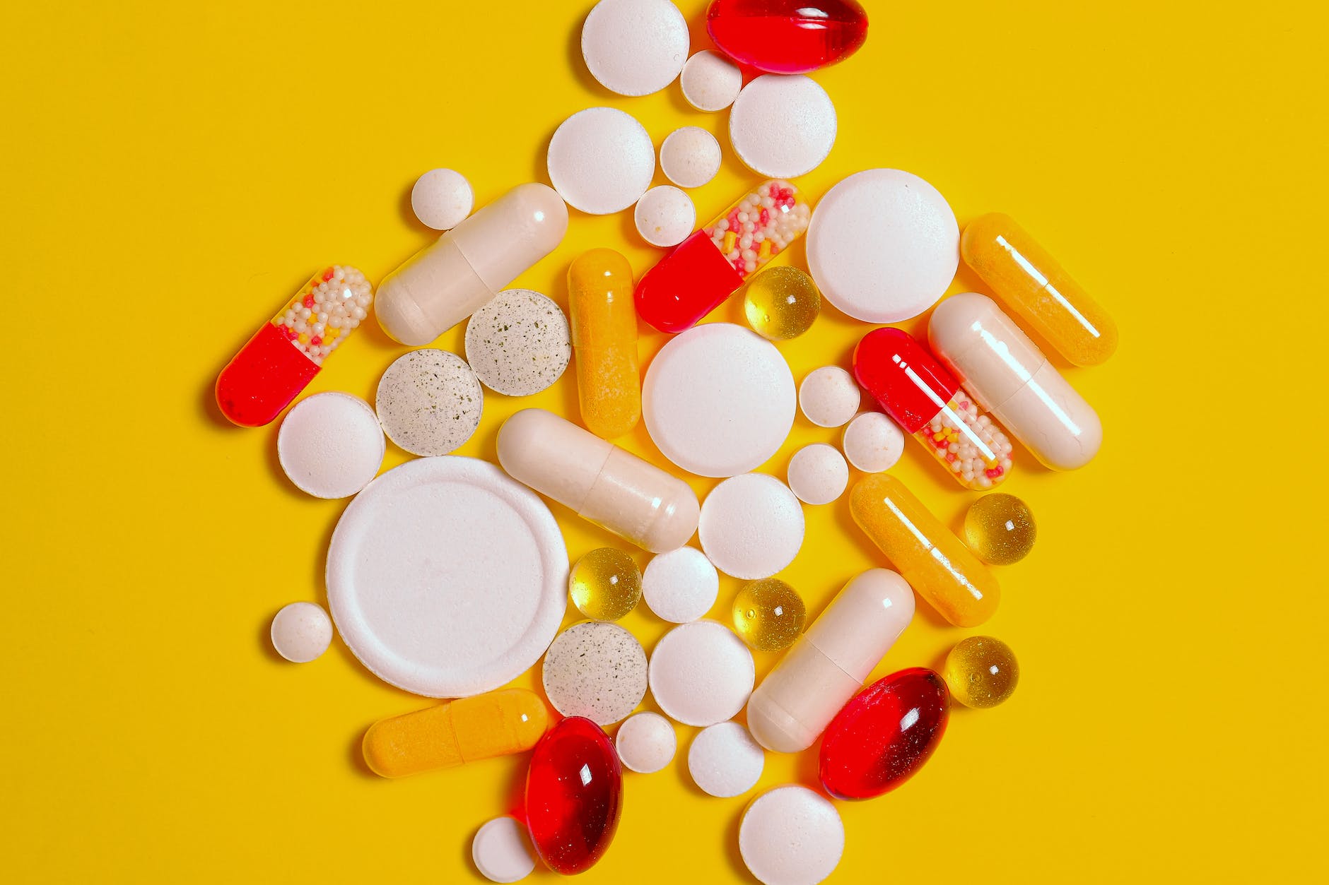 yellow background and numerous different pills and capsules