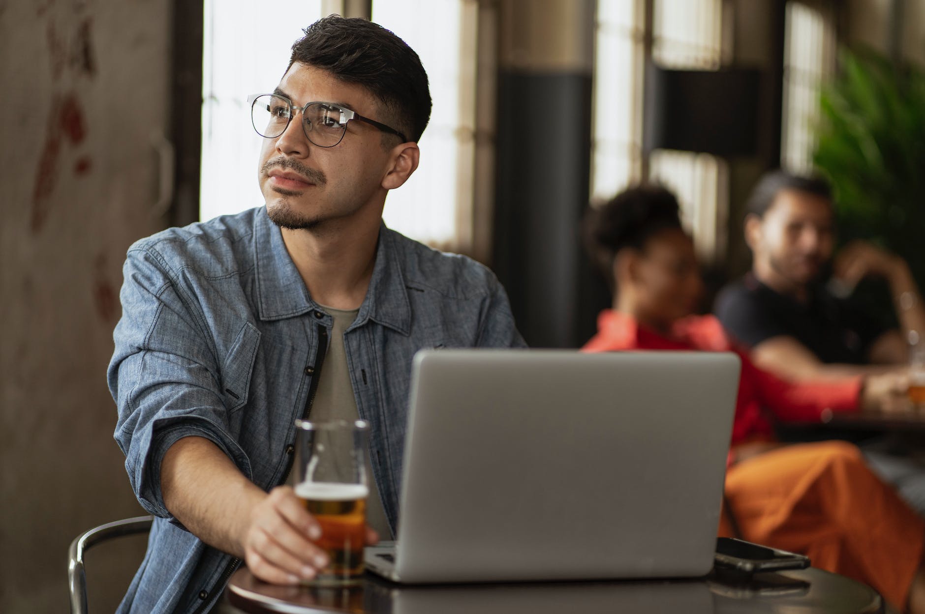 man in bar using laptop and drinking beer